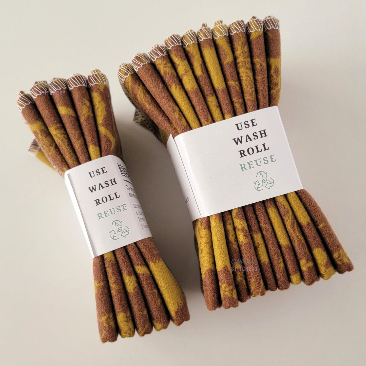 Two packages of the Brown Trees NonPaper Towels, shown on their side so display the 5-pack and 10-packs. The side of the paper tag says "use, wash, roll, reuse" and has the recycling logo with a leaf in the center, to symbolize they are biodegradable.
