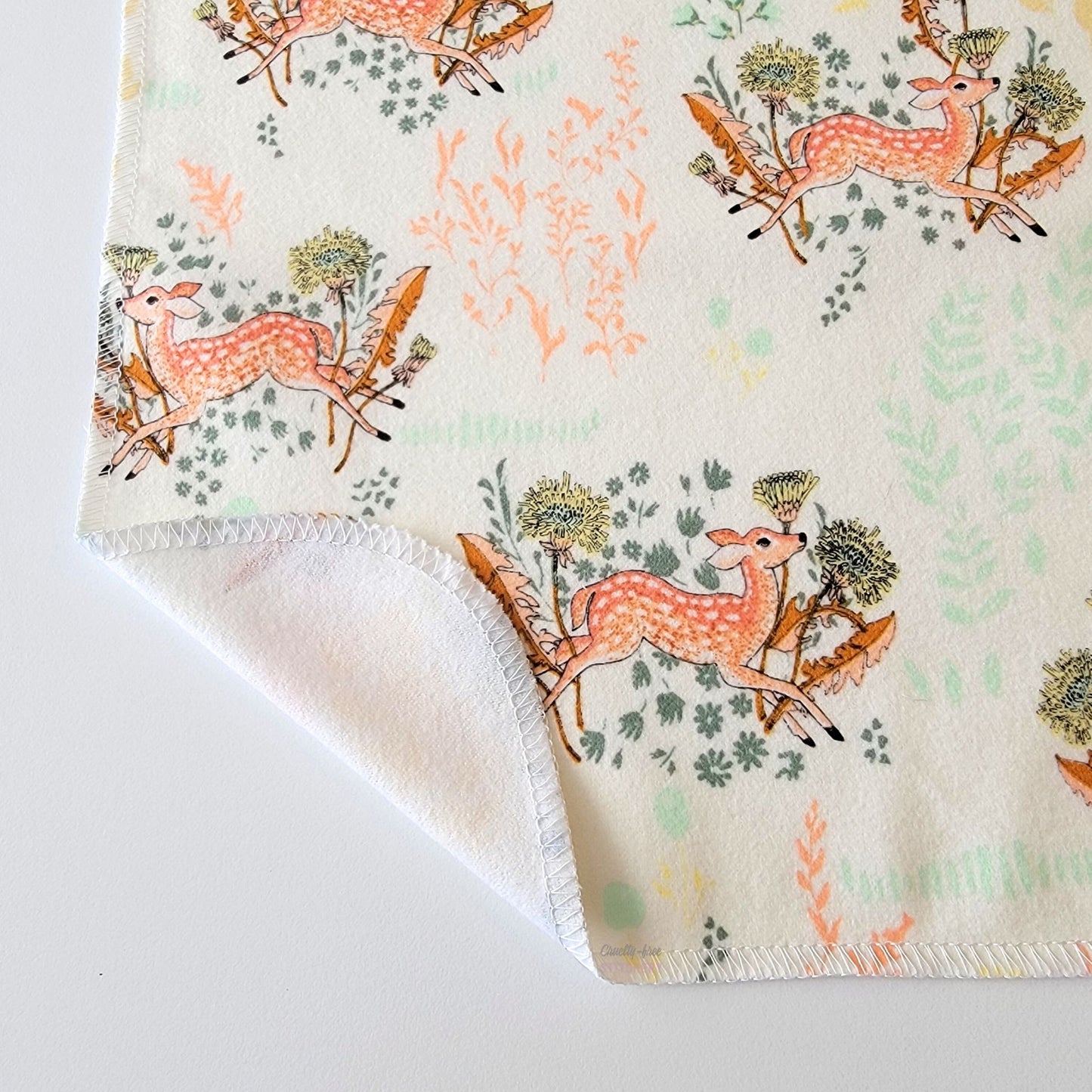 The Dandelion Doe NonPaper Towel, shown close-up with the bottom corner folded back to show they are unprinted on the back side, and are one layer.