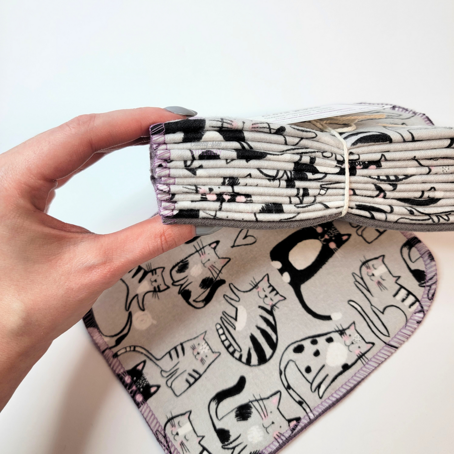 Holding the stack of bundled cloth wipes to show that there are twelve. The wipes are folded in half.