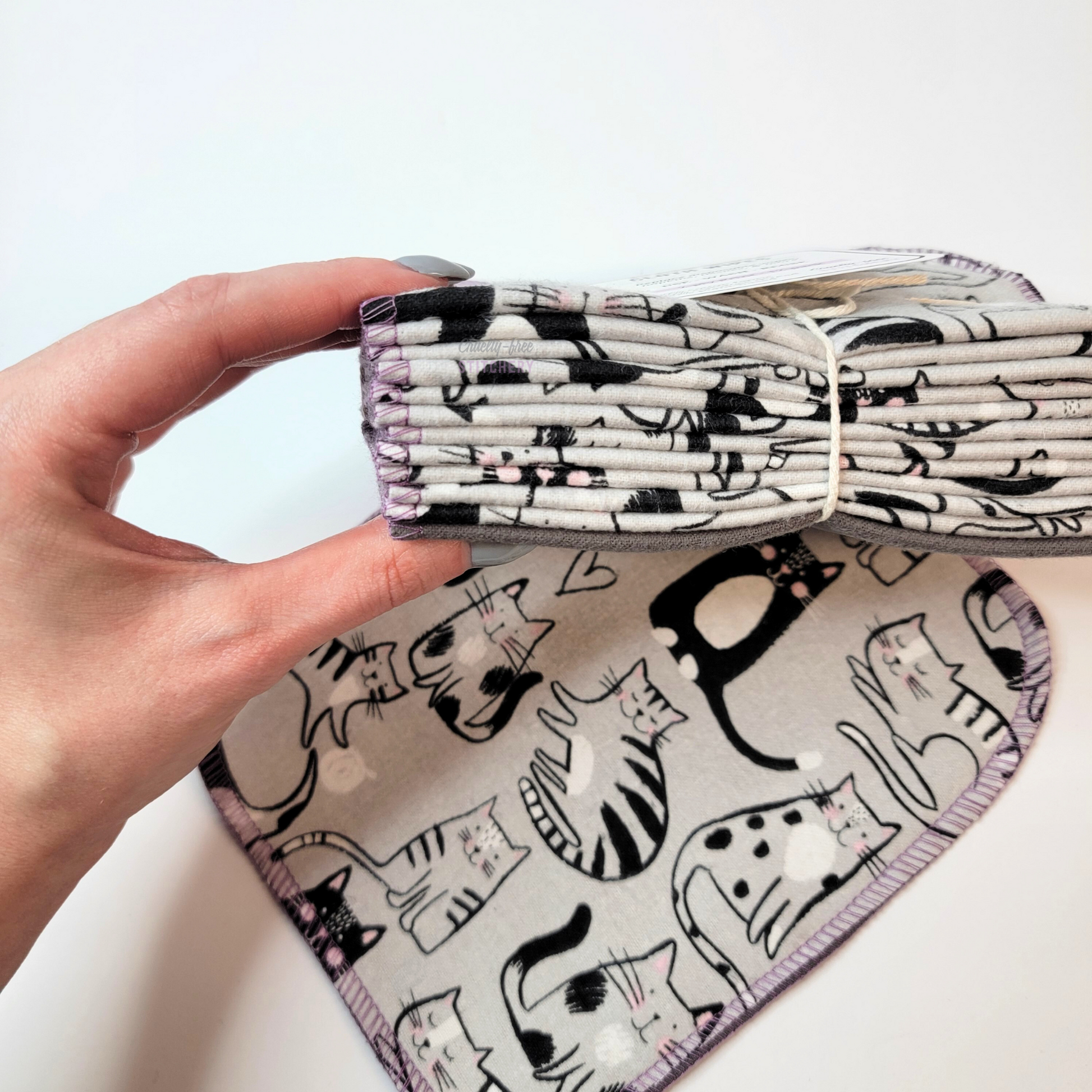 Holding the stack of bundled cloth wipes to show that there are twelve. The wipes are folded in half.