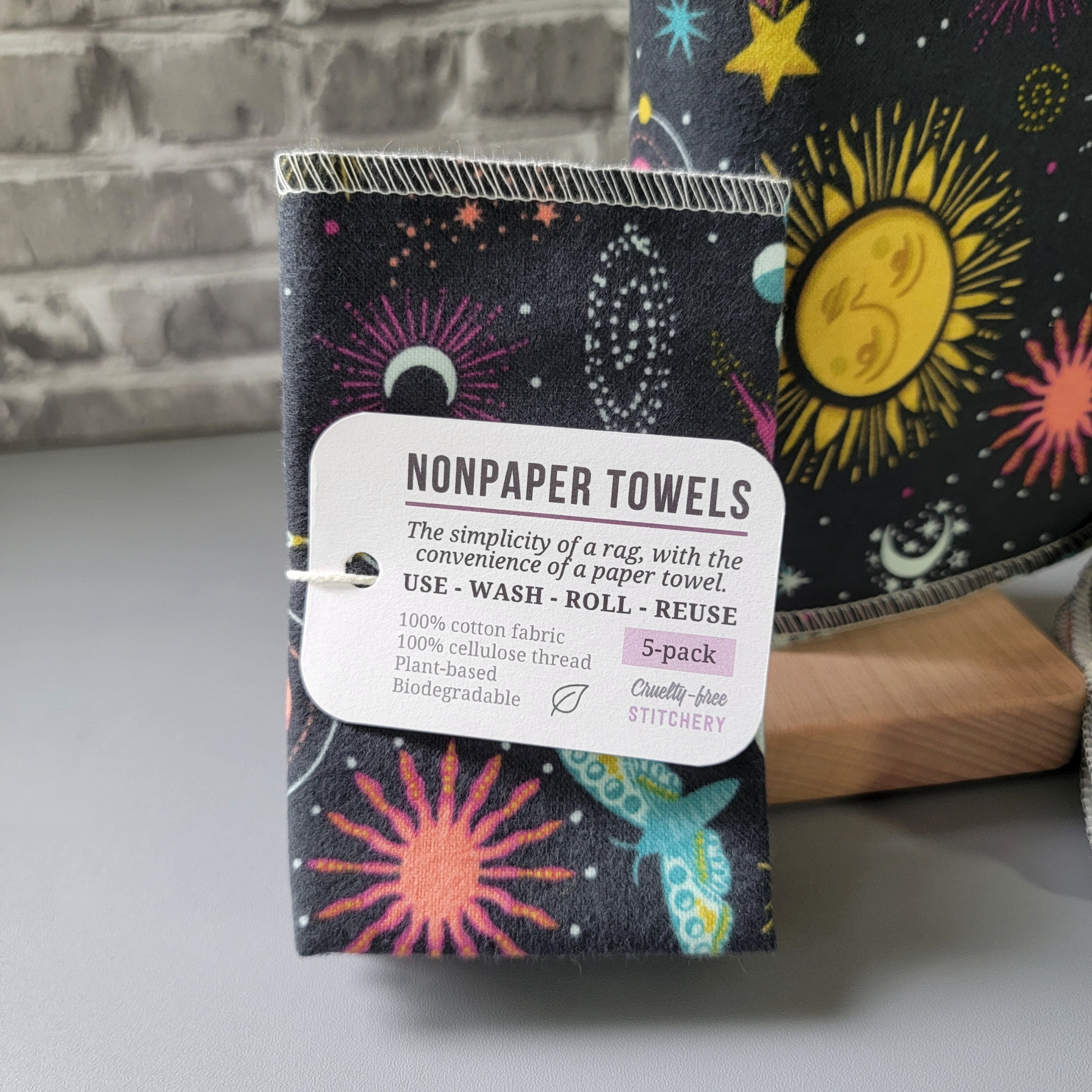 A close-up of the 5-pack, the tag says "NonPaper Towels, the simplicity of a rag with the convenience of a paper towel. Use, wash, roll, reuse. 100% cotton fabric, 100% cellulose thread. Plant based, biodegradable. 5-pack. Cruelty-Free Stitchery."