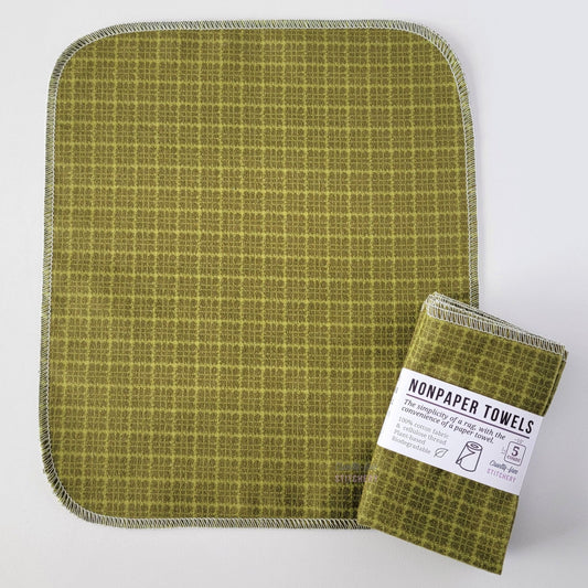 An unfolded Green Kitchen Plaid NonPaper Towel, next to a bundled 5-pack. The towel is a rectangle with rounded corners, stitched around the edges with white thread. The bundled pack is folded up with a paper wrapper that says "NonPaper Towels, the simplicity of a rag with the convenience of a paper towel"