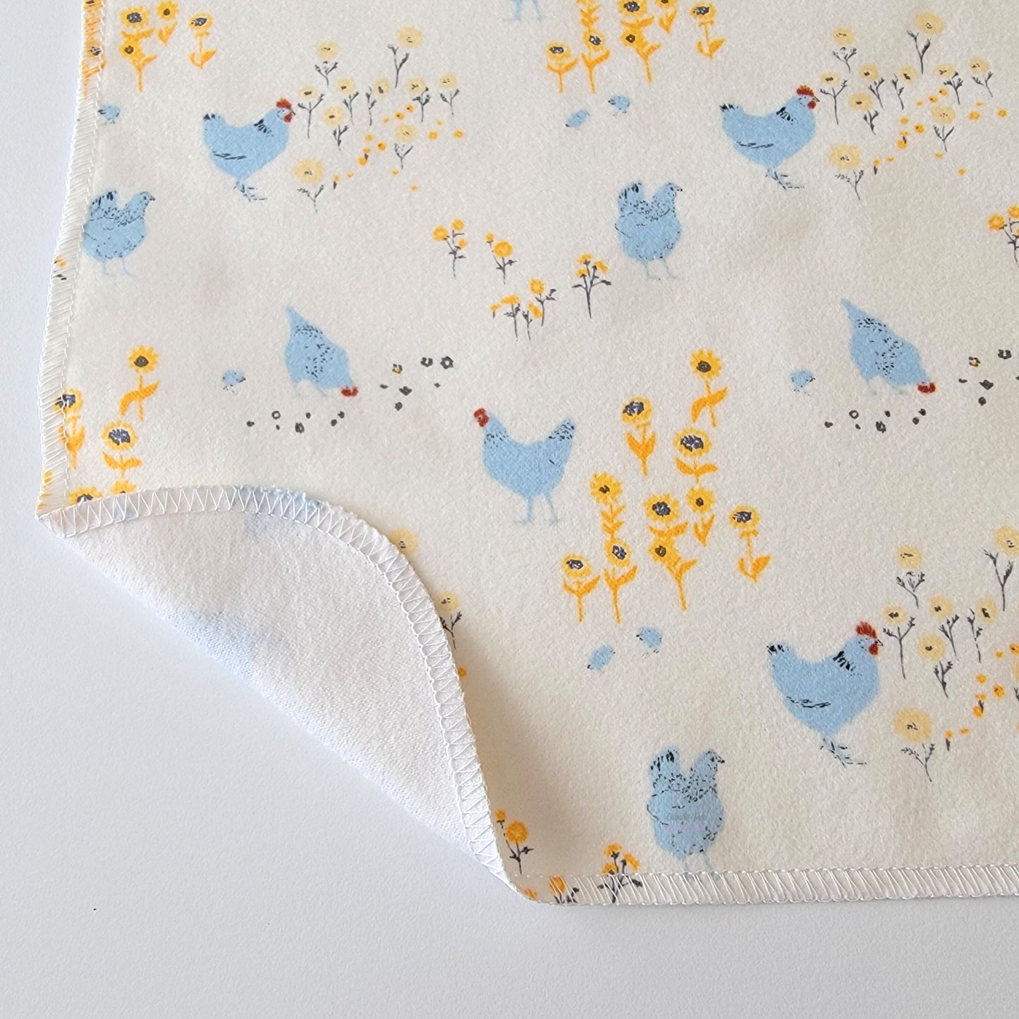 The Hens and Chickens NonPaper Towel, shown close-up with the bottom corner folded back to show they are unprinted on the back side, and are one layer.
