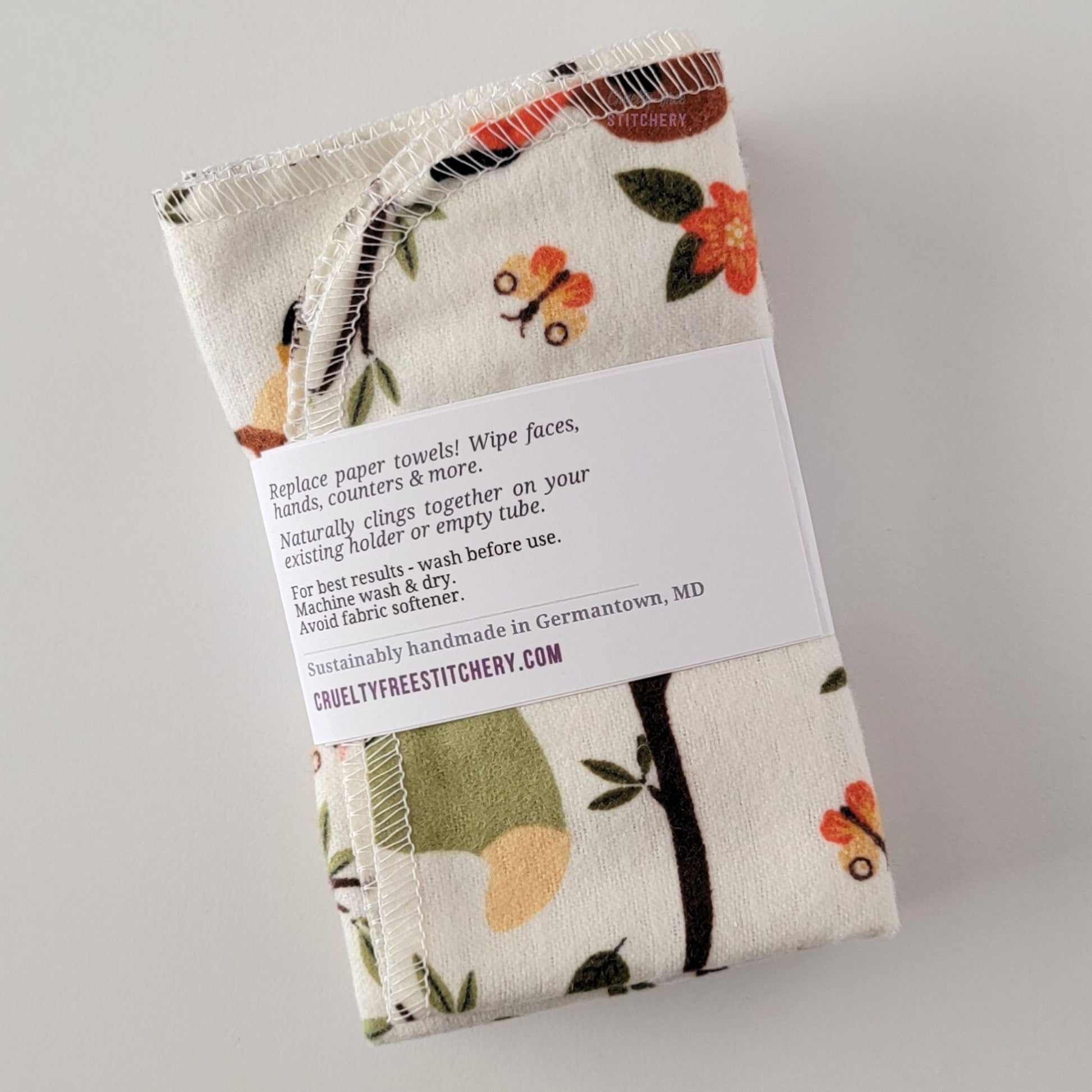 The back of a packaged bundle of the Ivory Foxes NonPaper Towels. The tag reads "Replace paper towels! Wipe faces, hands, counters, and more. Naturally clings together on your existing holder or empty tube. For best results - wash before use. Machine wash and dry. Avoid fabric softener. Sustainable handmade in Germantown, Maryland. CrueltyFreeStitchery dot com."