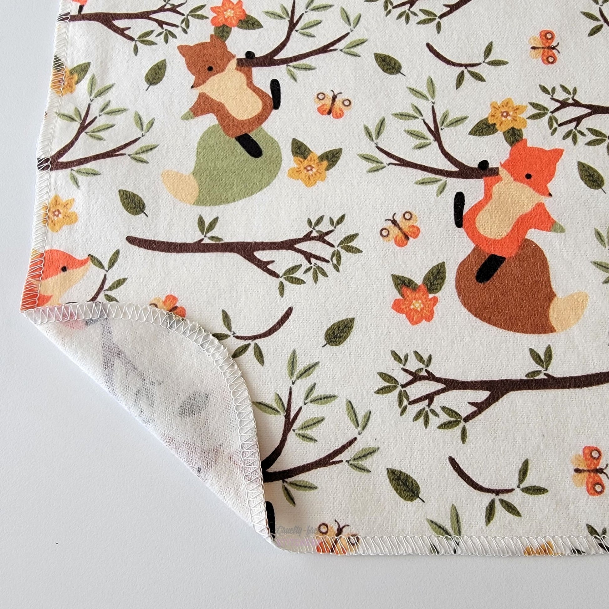 The Ivory Foxes NonPaper Towel, shown close-up with the bottom corner folded back to show they are unprinted on the back side, and are one layer.
