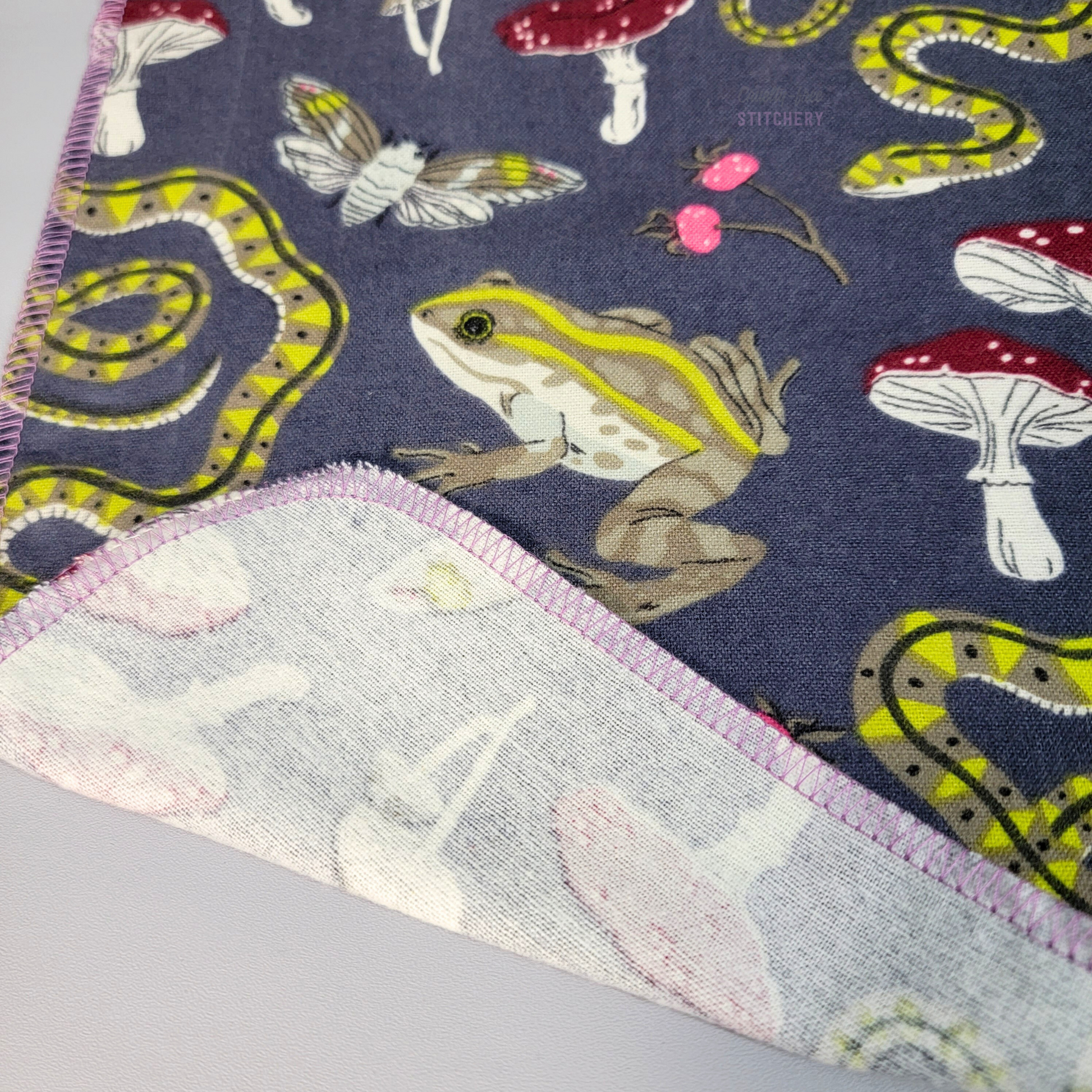 The bottom corner of one NonPaper Towel with the edge folded back, to show that the print is one-sided and the other side is white with the print showing through.