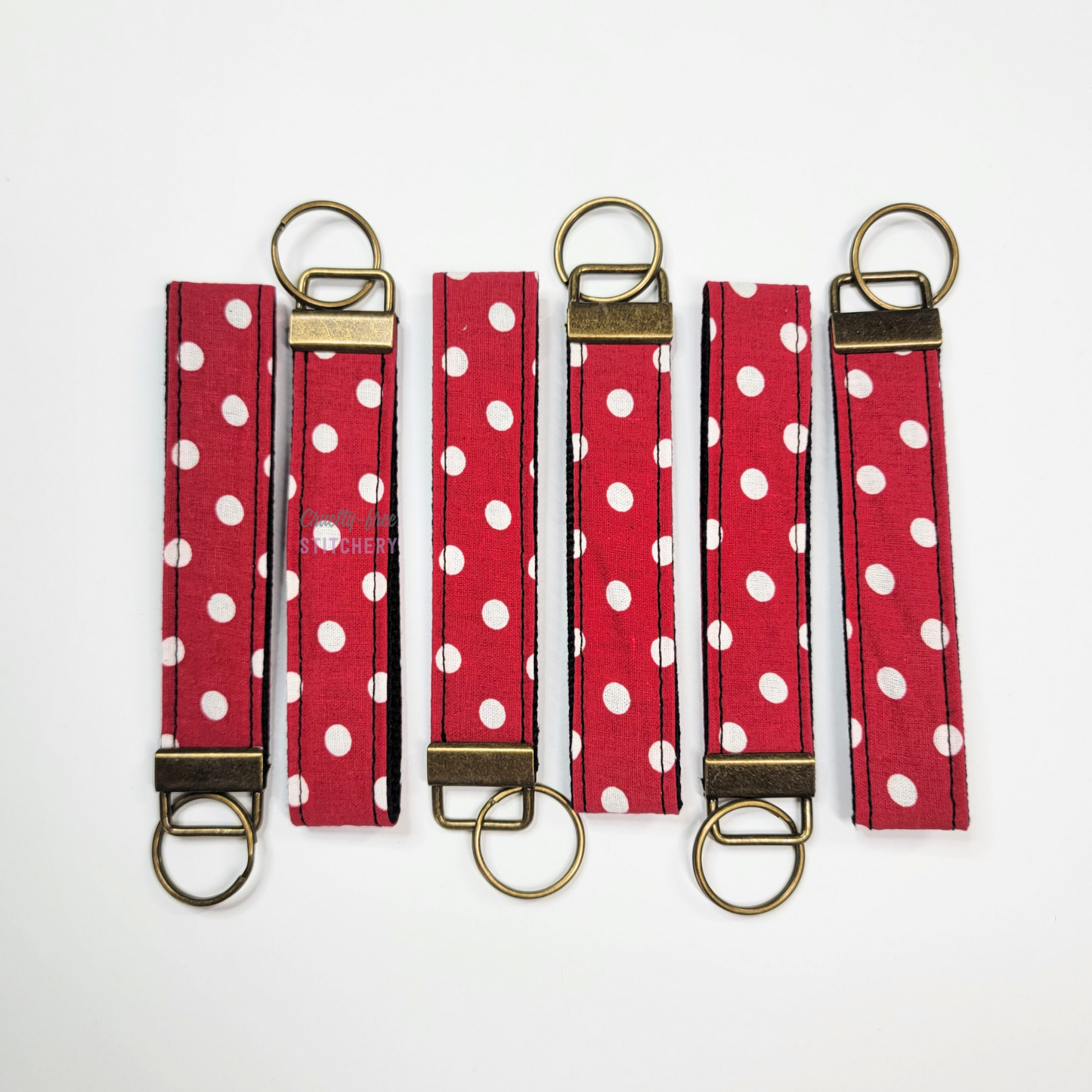 Red and white polka dots key fob wristlets arranged in neat rows with alternating directions.