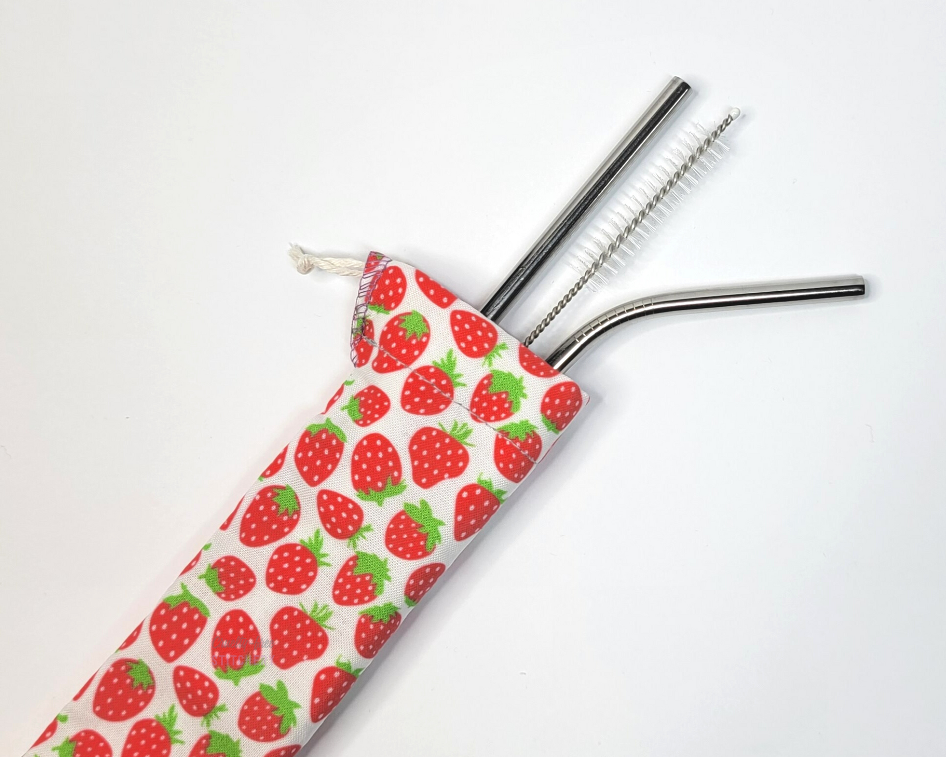 Reusable straw pouch with stainless steel straws sticking out the top. The fabric of the pouch is white with tiny red strawberries and it has a drawstring closure.