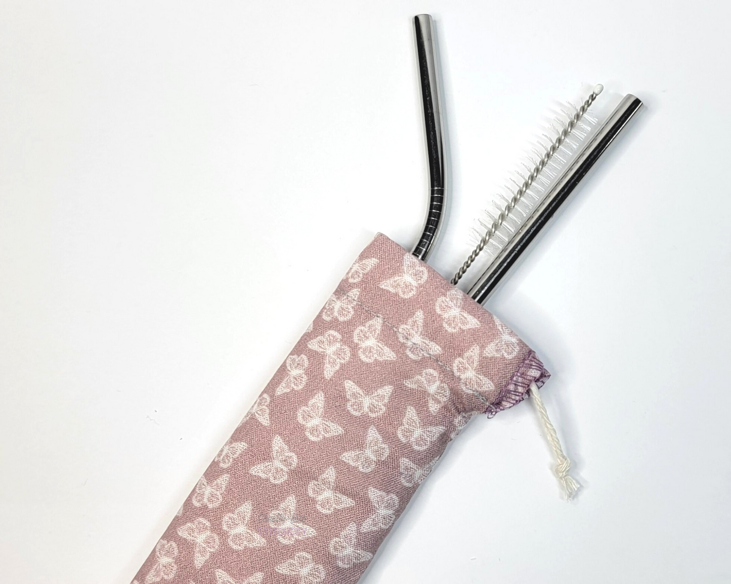 Reusable straw pouch with stainless steel straws sticking out the top. The fabric of the pouch is a light pink mauve with tiny white butterflies and it has a drawstring closure.