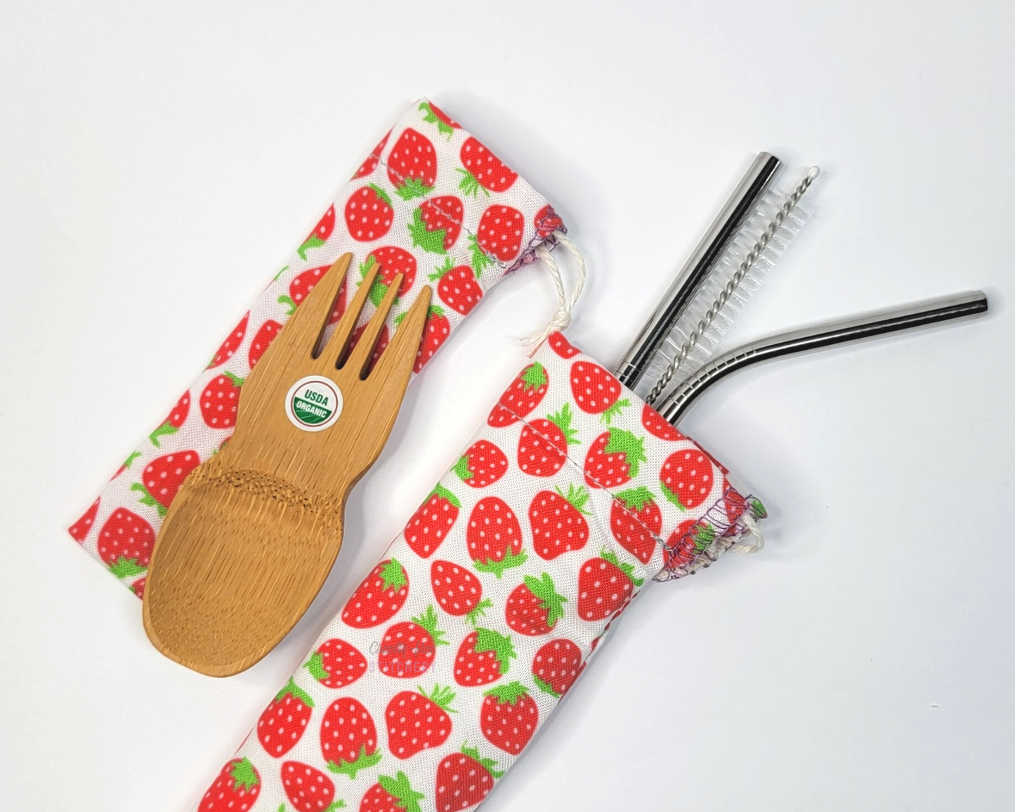 Reusable bamboo spork and stainless steel straw pouch set. The pouches are both white with tiny red strawberries.