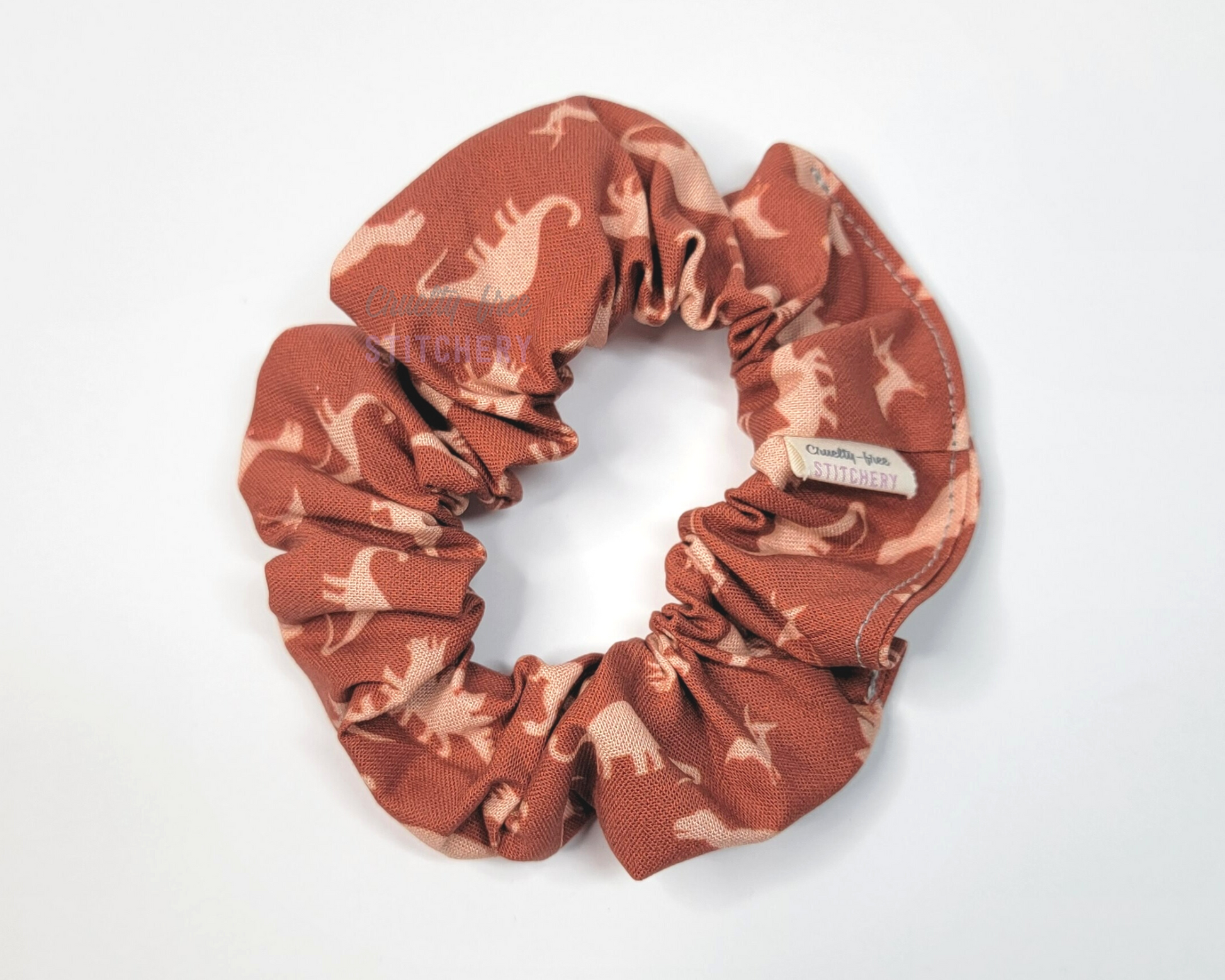 A dark orange scrunchie with light orange dinosaurs.