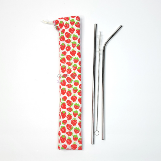 Reusable straw pouch in the strawberry print laying vertically next to a straw cleaner brush, a straight stainless steel straw, and a bent stainless steel straw.