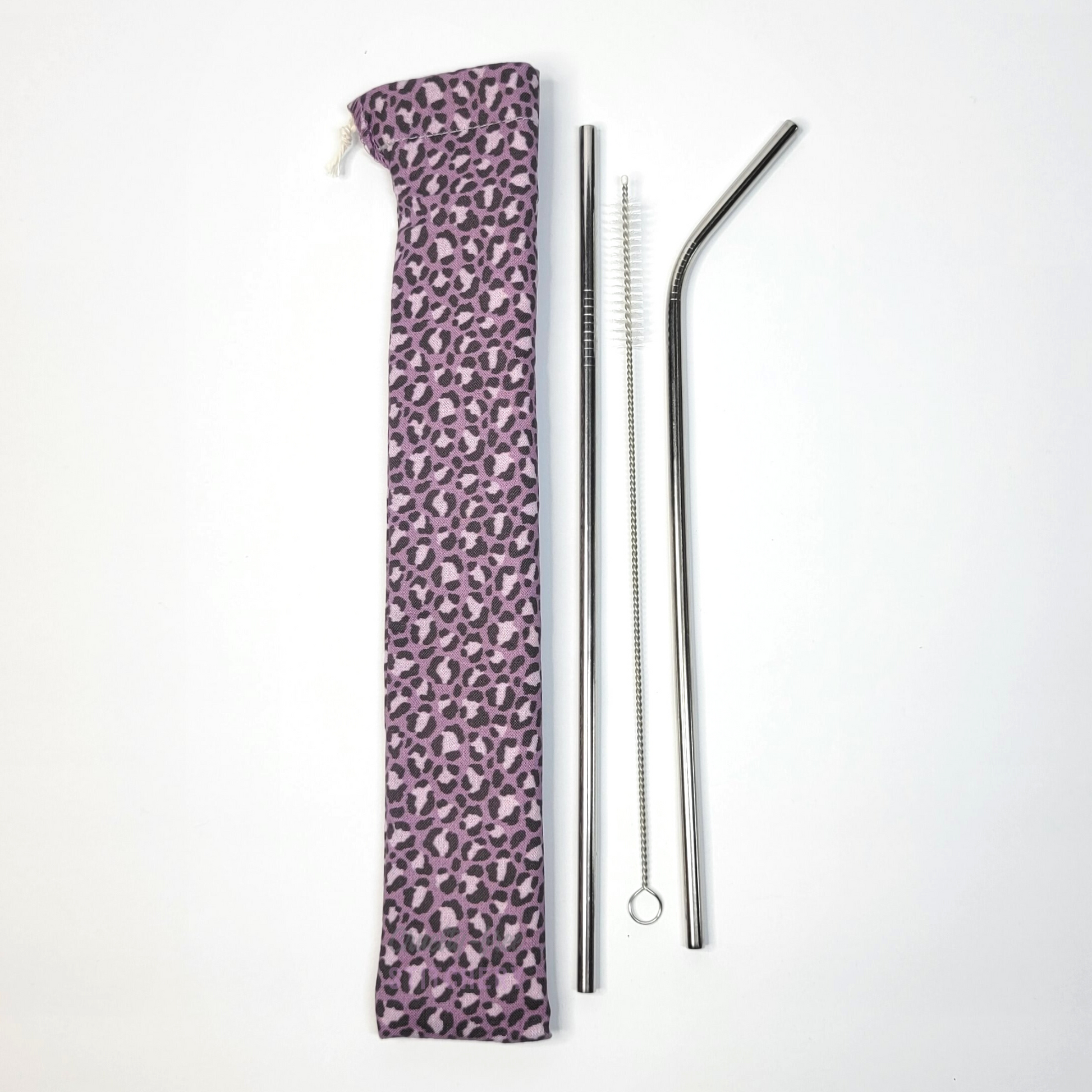 Reusable straw pouch in the same violet leopard print laying vertically next to a straw cleaner brush, a straight stainless steel straw, and a bent stainless steel straw.
