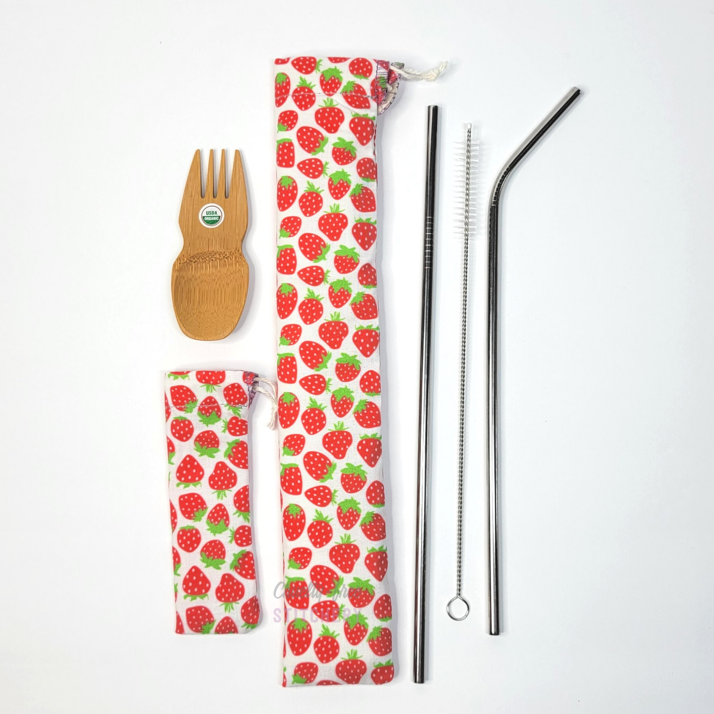 All contents of this set, a bamboo spork, strawberry spork pouch, matching strawberry straw pouch, and stainless steel straws.