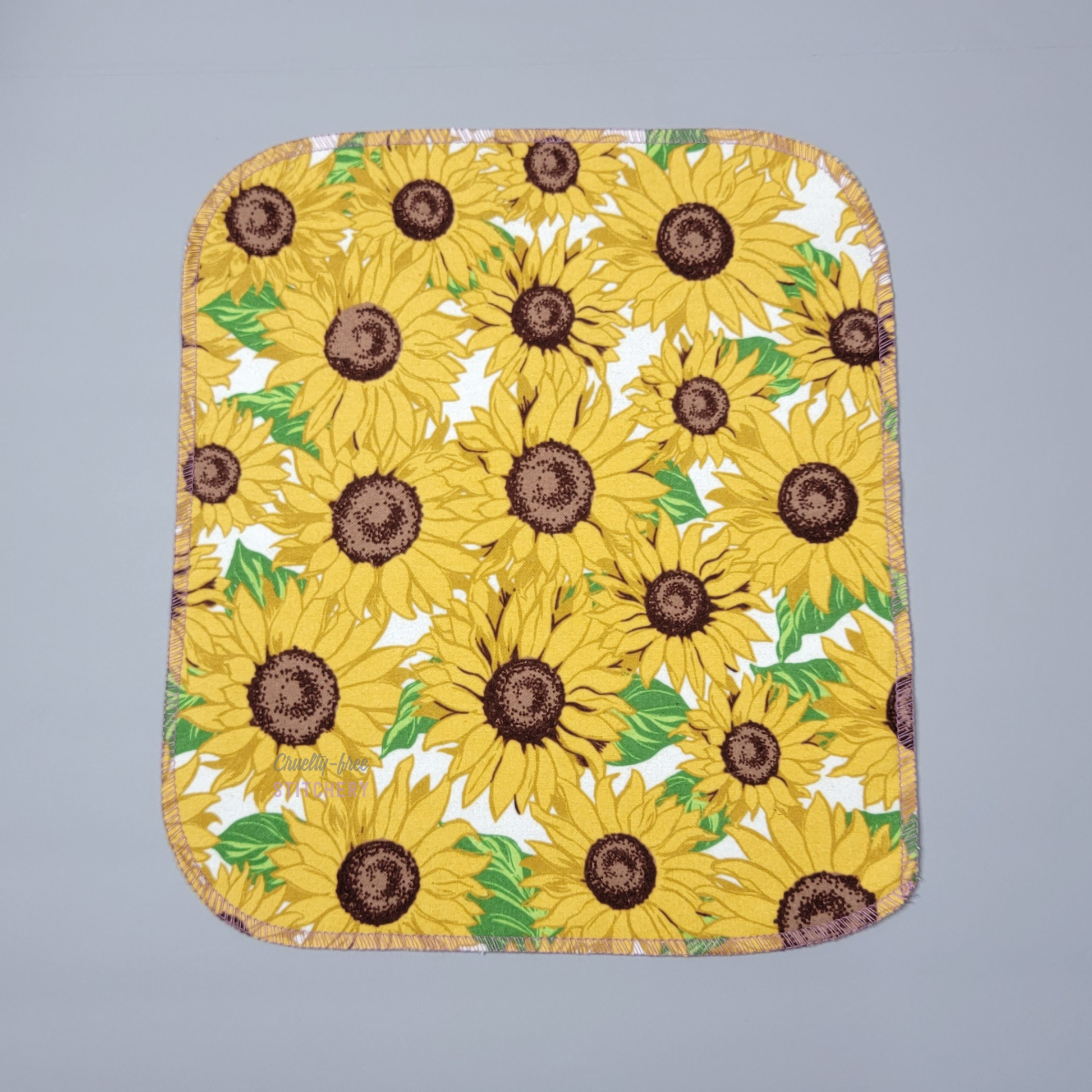 One sunflower print NonPaper Towel laid flat. The shape is a slight rectangle with rounded corners.