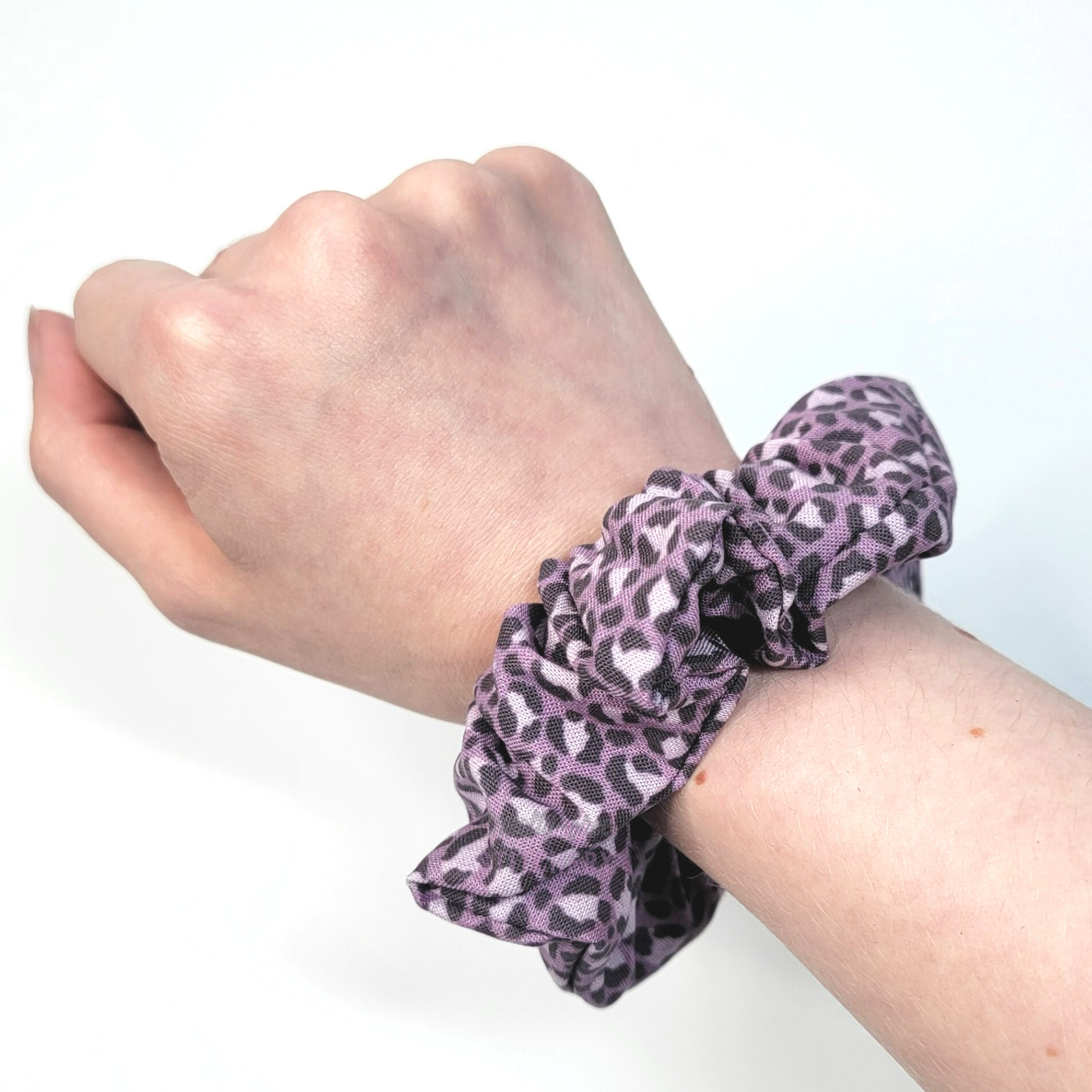 Muted violet purple leopard print Scrunchie shown on my wrist for size reference. Fabric sticks out about an inch from the center of the scrunchie.