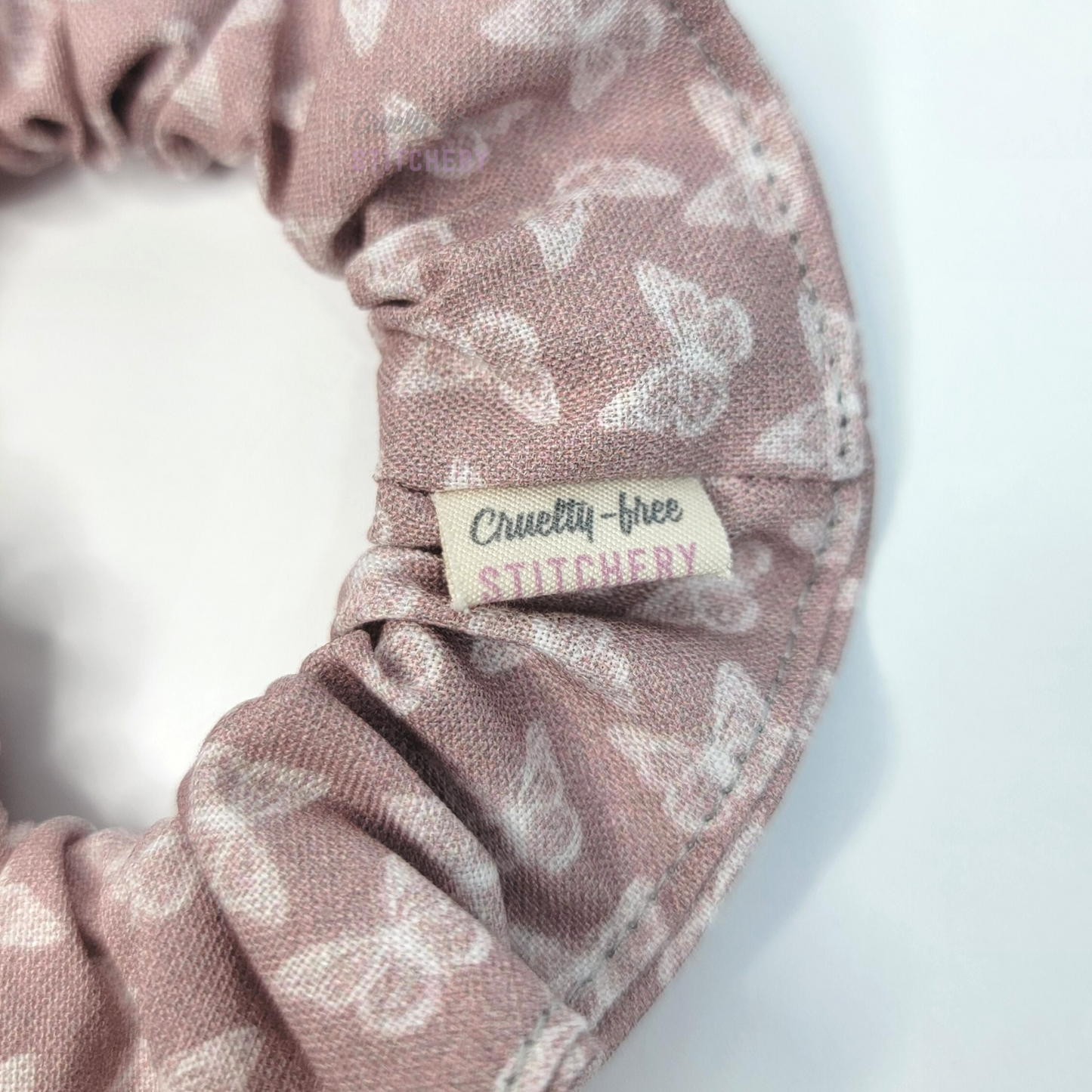 Close-up of the scrunchie with a small white tag with the Cruelty-Free Stitchery logo.