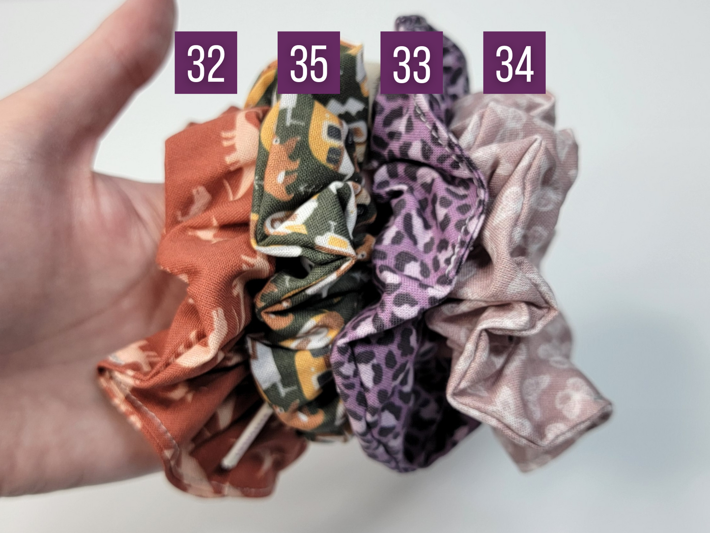 Comparison of prints. 32 is orange with dinosaurs, 35 is dark green with camping motifs, 33 is a violet leopard print, 34 is a mauve pink with white butterflies.