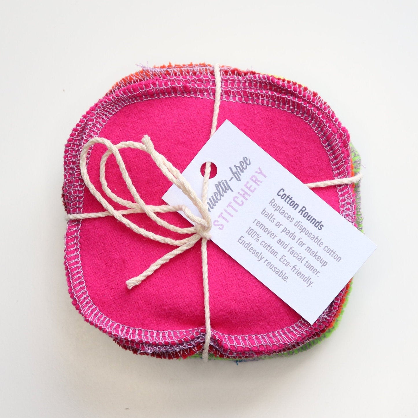 Bundled pack of rainbow reusable cotton rounds tied with string and a small white paper tag.