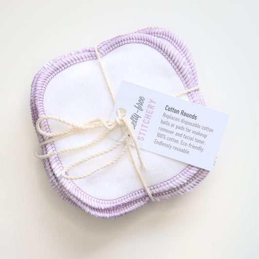 A bundle of white reusable cotton rounds - tied with a natural-colored string and a small paper tag with the cruelty-free stitchery logo.
