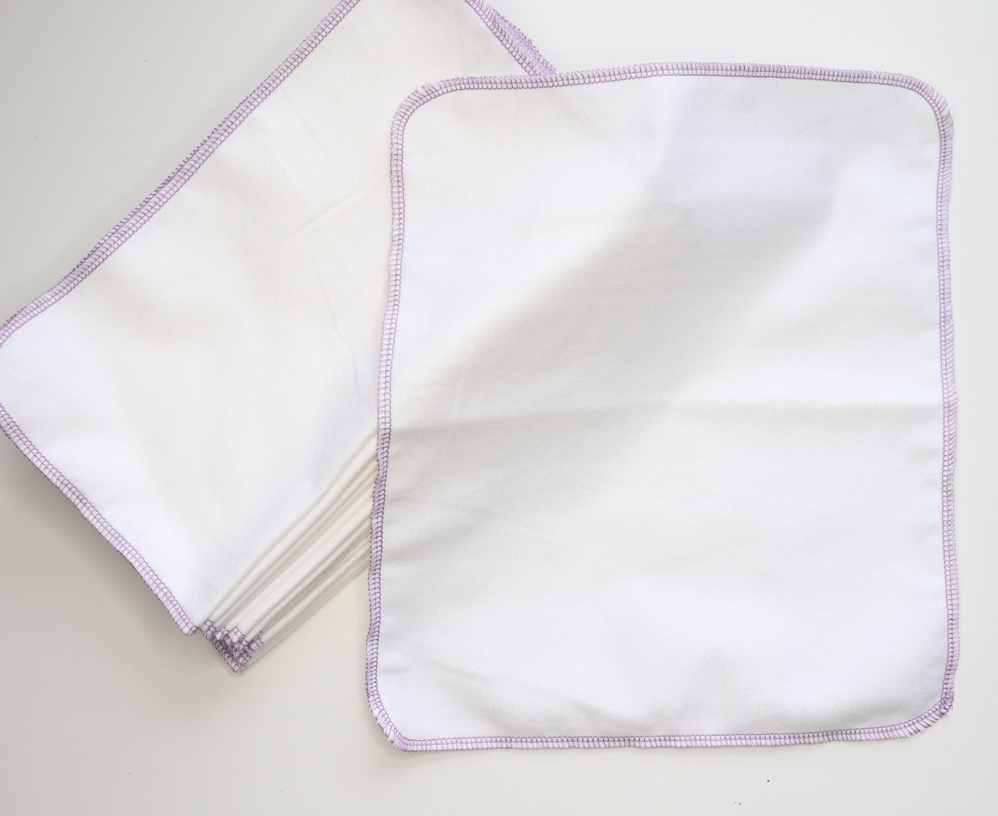 Solid white reusable NonPaper Towels. Stitched on the outside with a lilac purple thread.