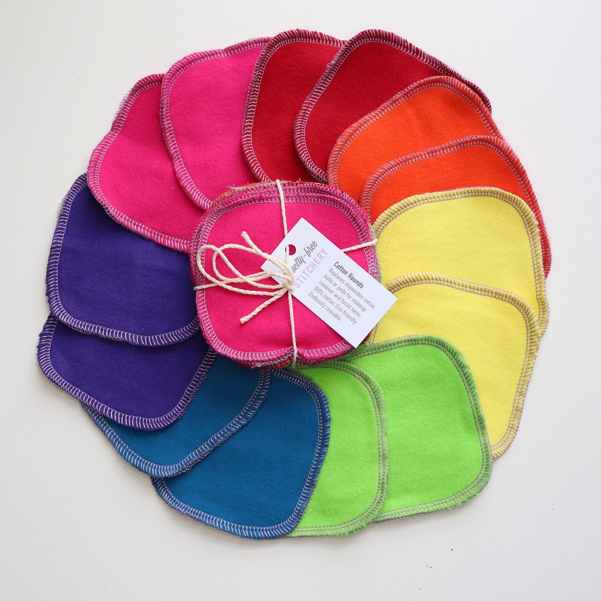 Cotton Rounds arranged in a circle with a bundled pack in the center. Bright rainbow solid colors, 2 each of hot pink, red, orange, yellow, lime green, blue, and purple.
