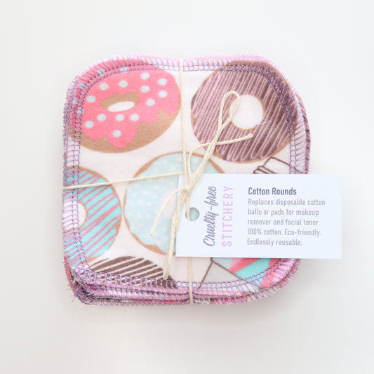 Bundled pack of the donuts print cotton rounds. The donuts are pink, light blue, and brown with stripes and sprinkles, and there are to-go coffee cups with pink and blue patterns.