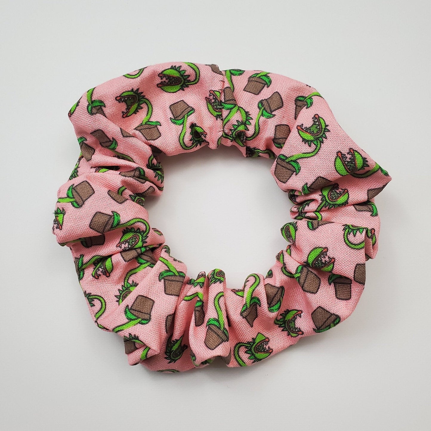 Pink scrunchie with tiny man-eating plants in brown pots.
