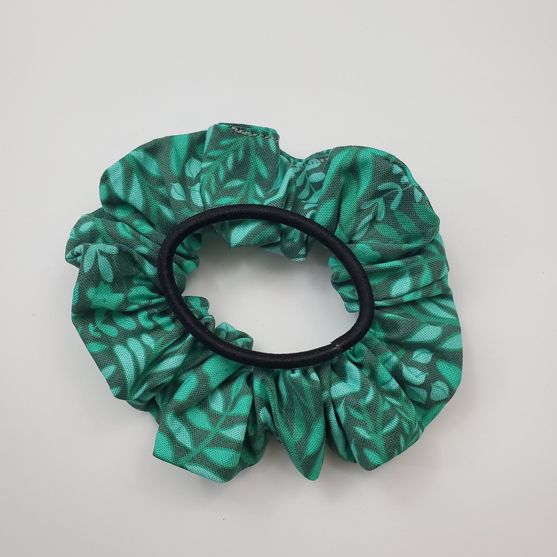 Green leaves scrunchie shown with a regular black hair tie on top for size reference. 