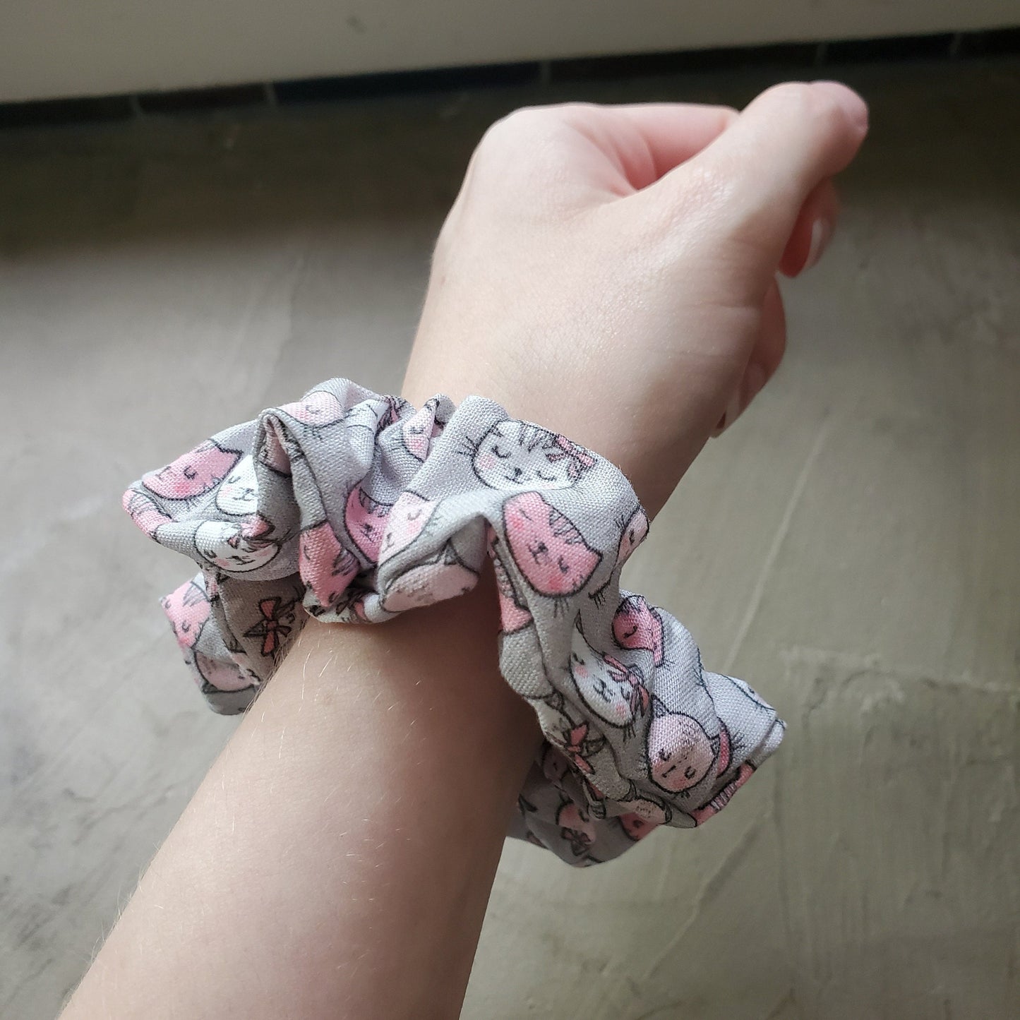 Grey and Pink Biodegradable Scrunchie on my wrist to show the size. It sticks out about an inch from my arm.