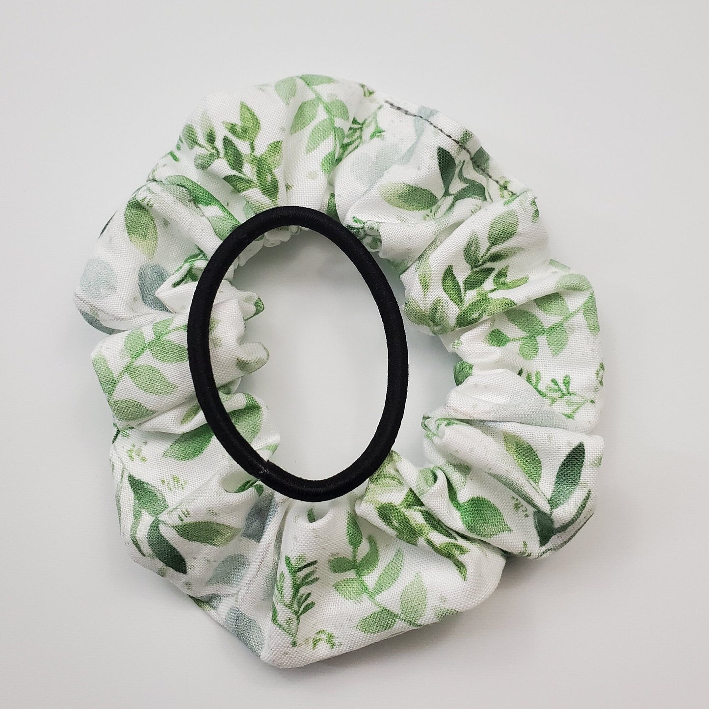 White with eucalyptus leaves Scrunchie with a regular black hair tie on top to show the size.