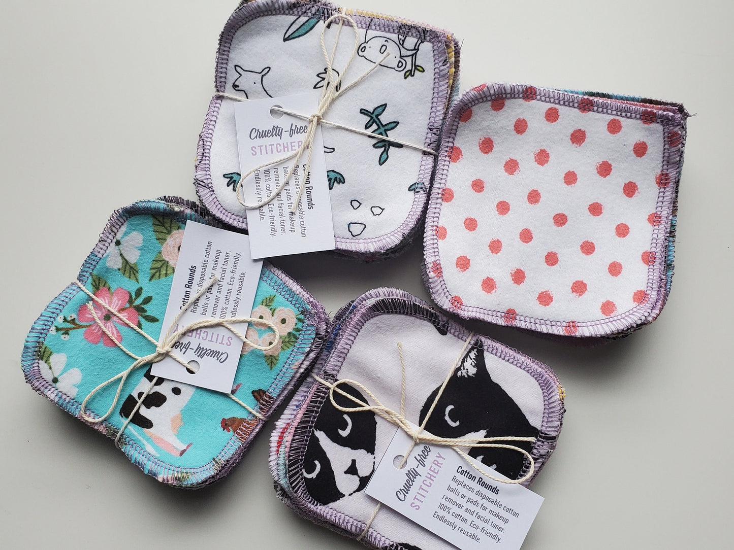 Four bundled packs of assorted print reusable cotton rounds tied with string and a small white tag.