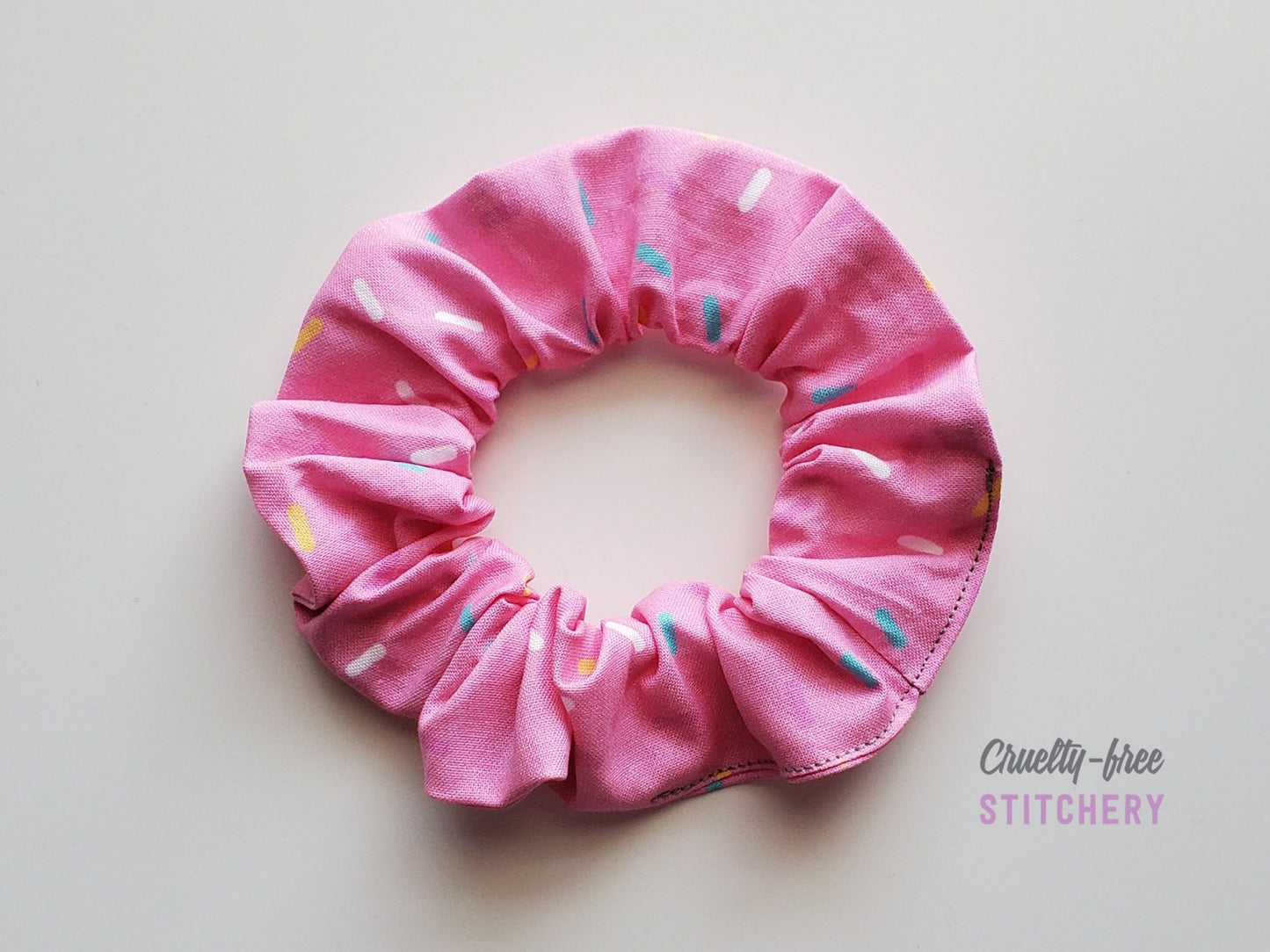 Pink with sprinkles print scrunchie on a white background.