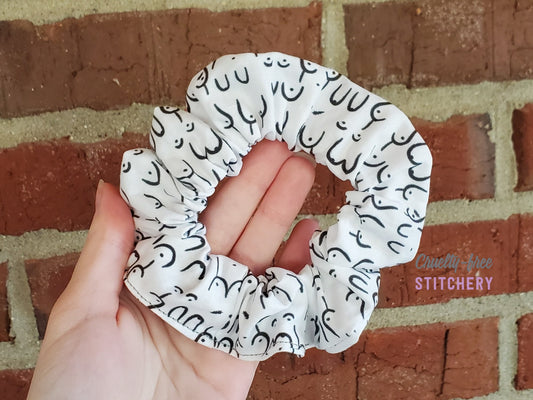 Scrunchie in a white with black drawn boobs print - boobs of all shapes and sizes, even full and partial mastectomy scars.