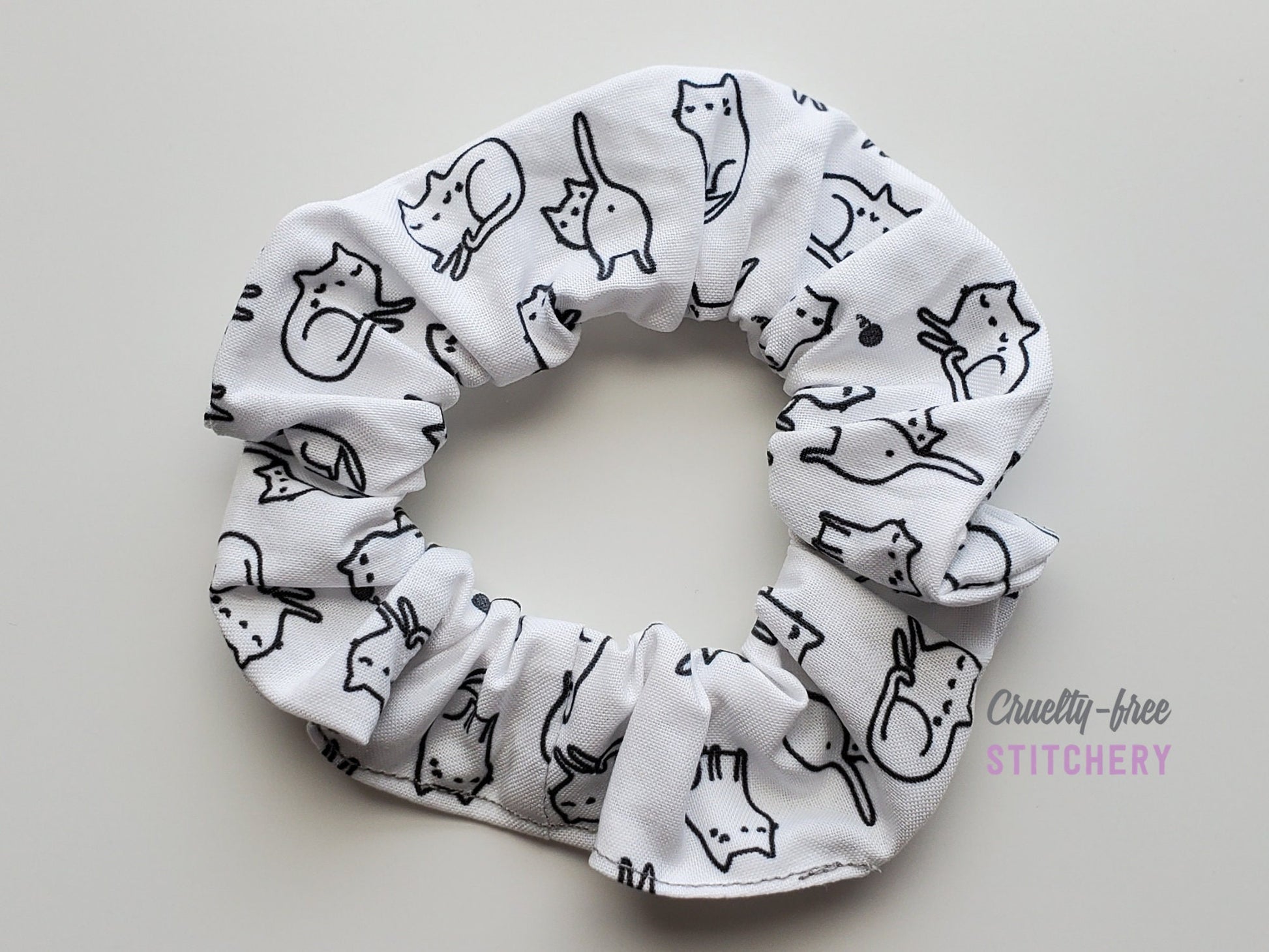 White with black outlined cats scrunchie on a plain white background.