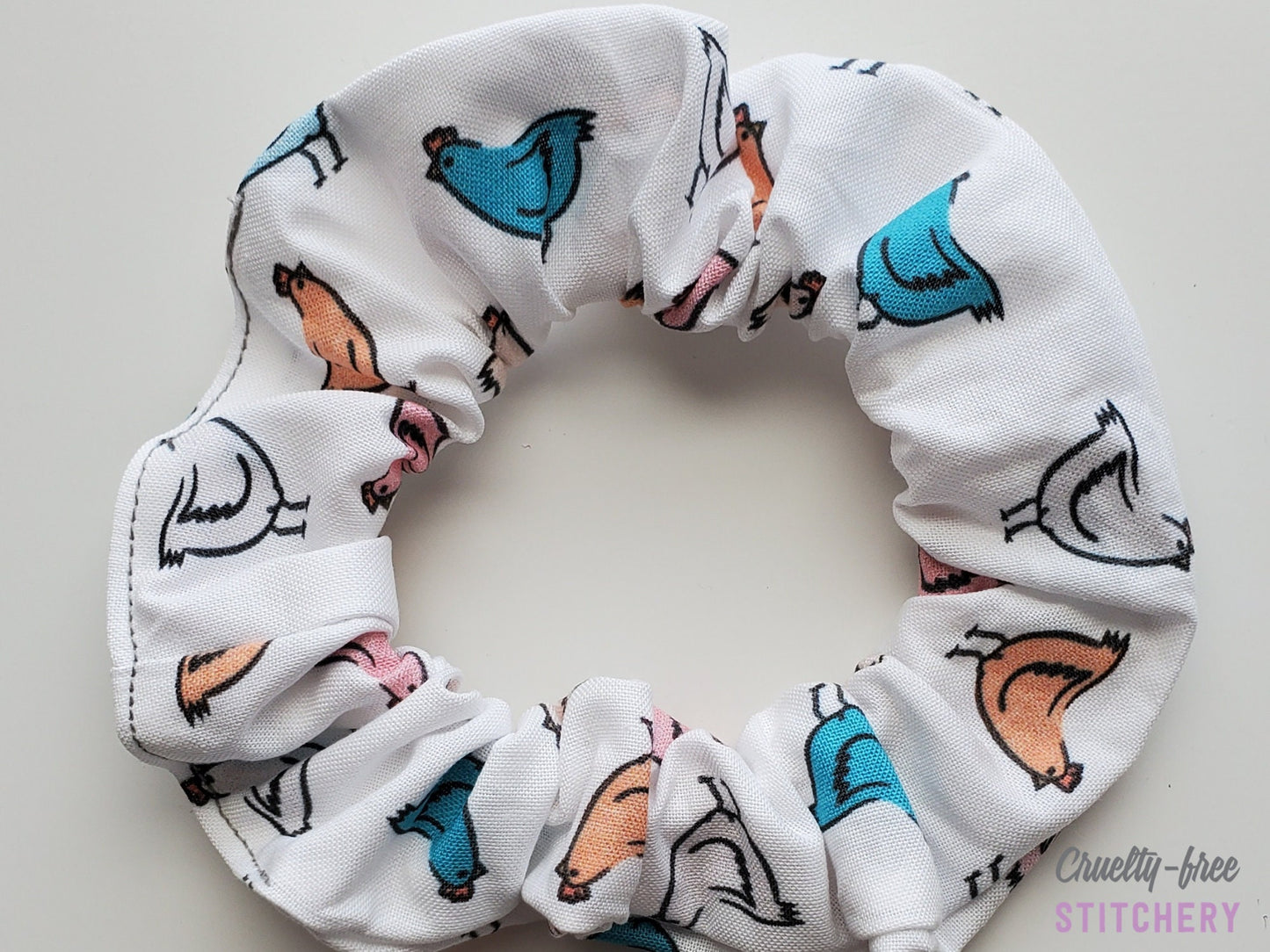 White with various colored chickens scrunchie on a plain white background.