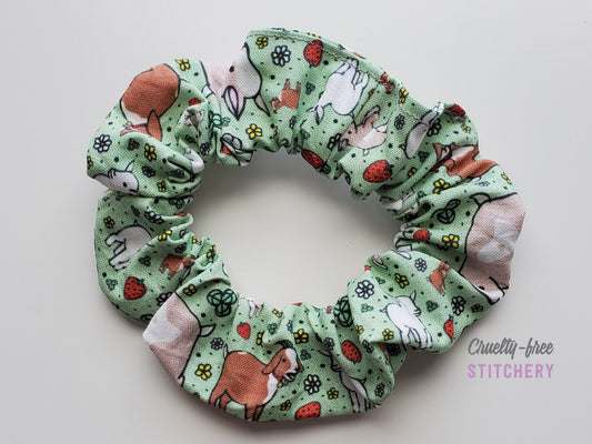 Green with tiny goats and strawberries print scrunchie on a white background.