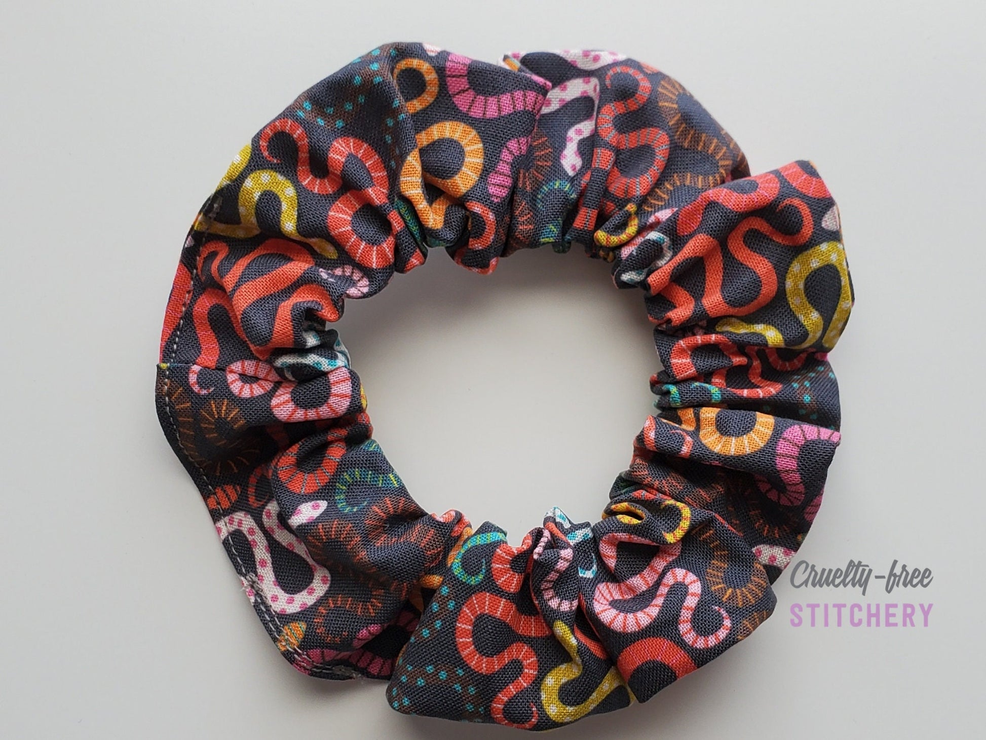Black with multicolored snakes print scrunchie on a white background.