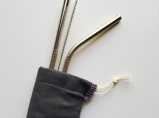 Reusable straw pouch with stainless steel straws sticking out the top. The fabric of the pouch is solid black and it has a drawstring closure.