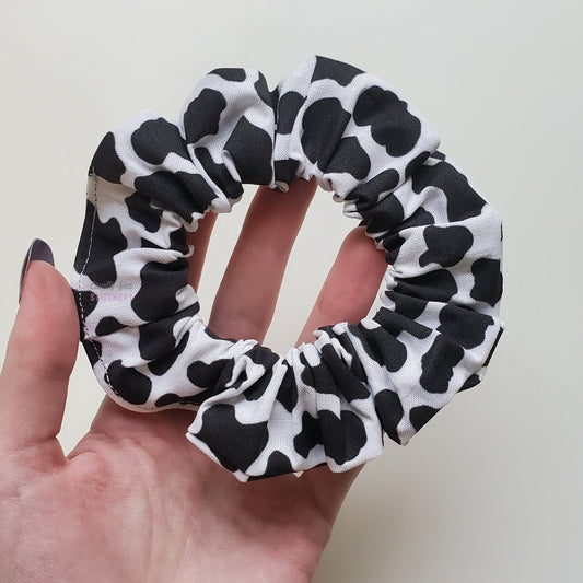 Black and white cow print scrunchie in my hand.