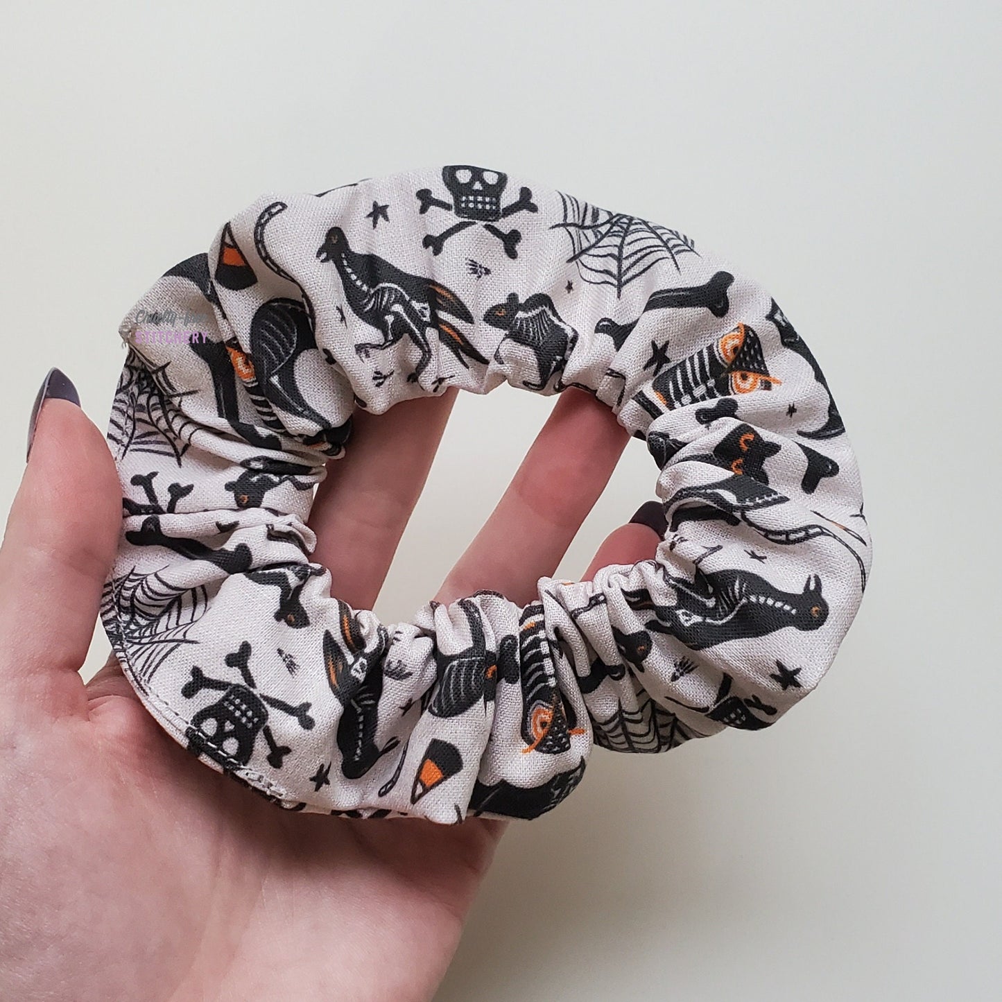 Halloween x-ray scrunchie in my hand for size reference. It covers my fingers and half of my palm.