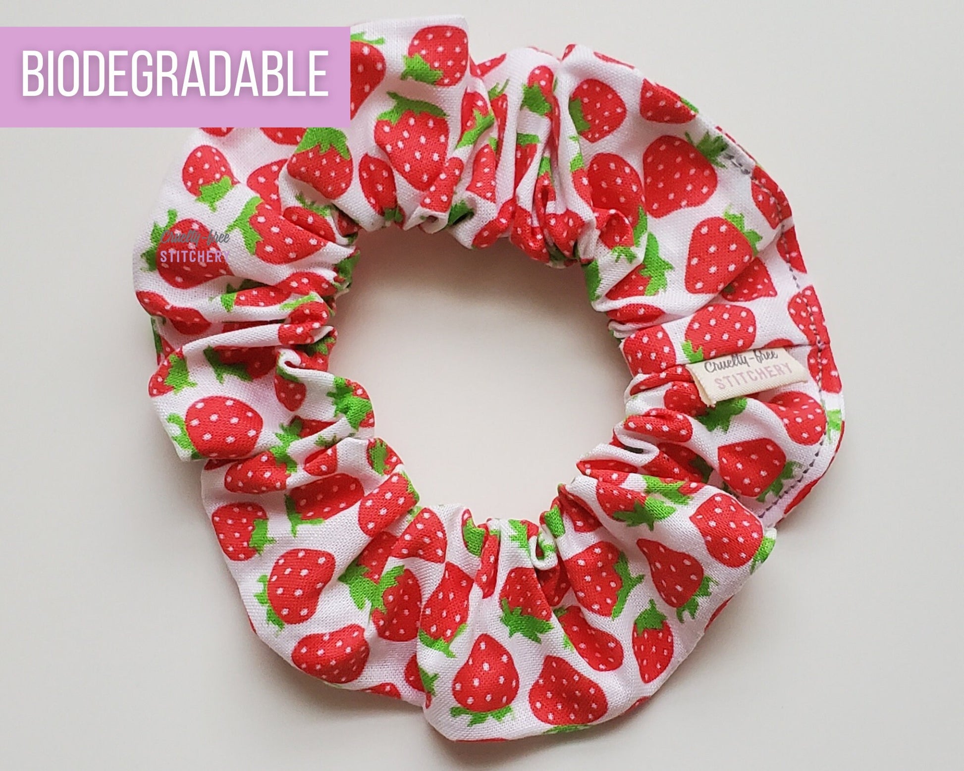 White with red strawberries print scrunchie. The strawberries are tiny and simple, and scattered across the fabric.