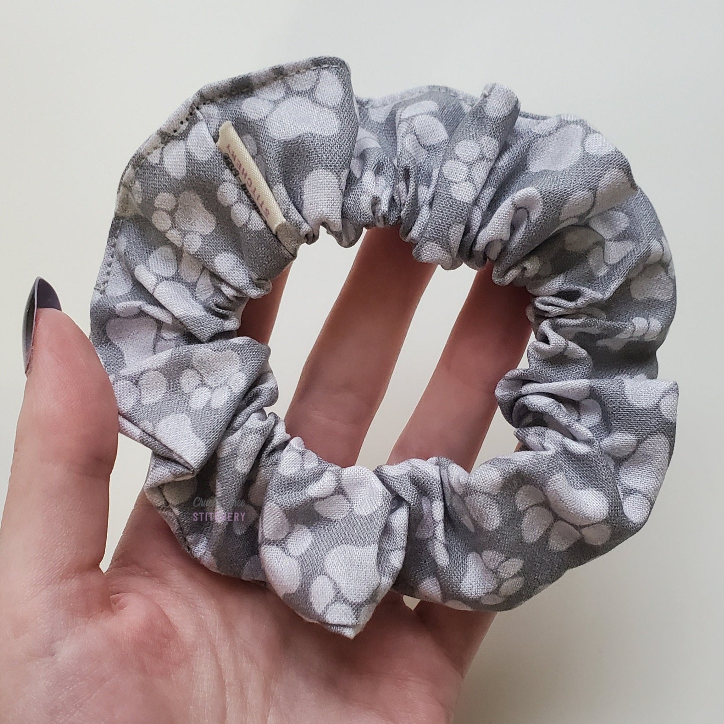 Gray paw print scrunchie in my hand.