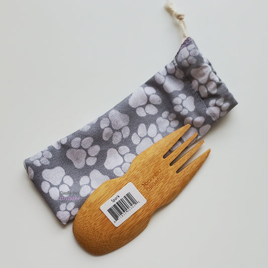 Reusable spork pouch laying diagonally next to an upside-down bamboo spork.