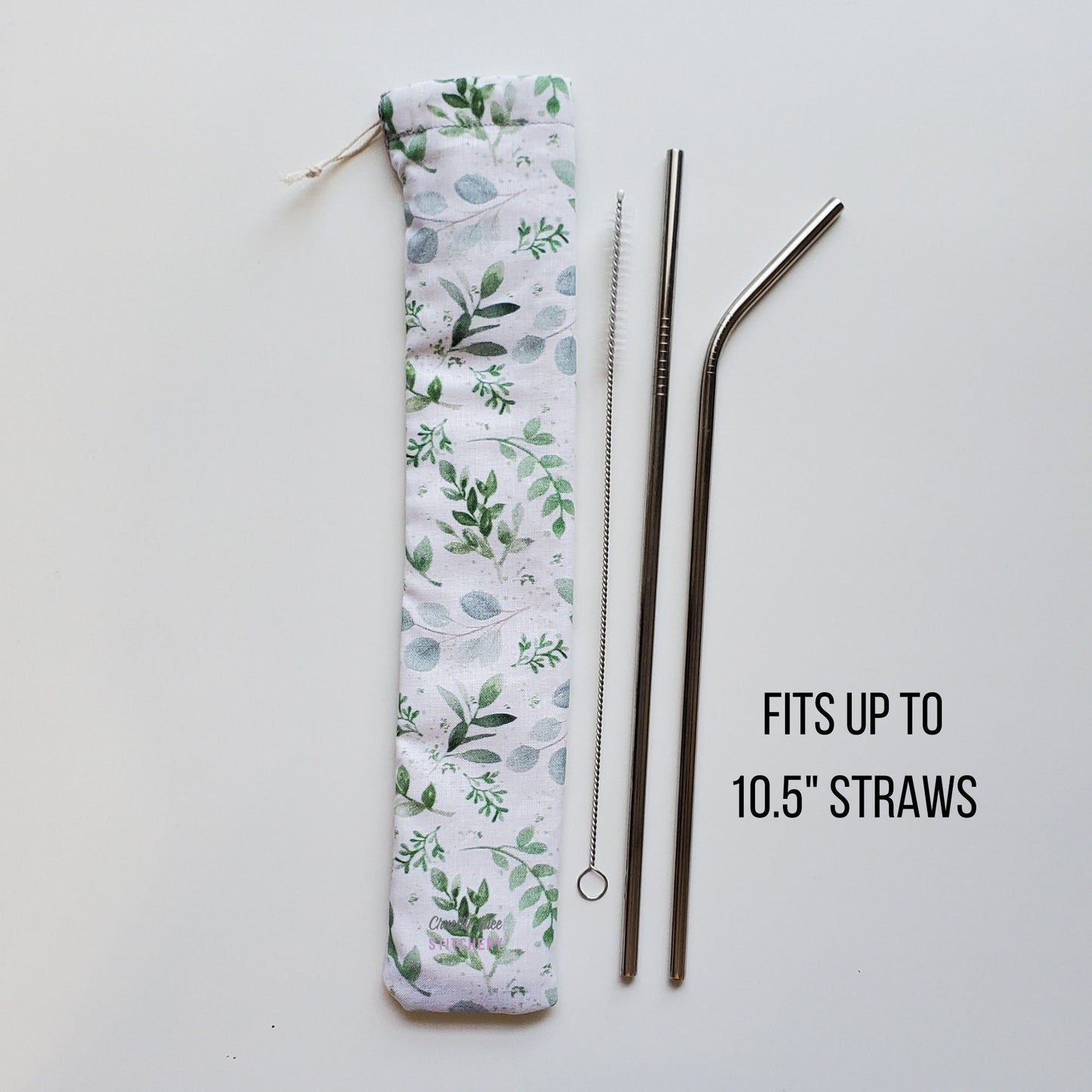 Reusable straw pouch in the same eucalyptus print laying vertically next to a straw cleaner brush, a straight stainless steel straw, and a bent stainless steel straw. Text reads &quot;fits up to 10.5 inch straws&quot;