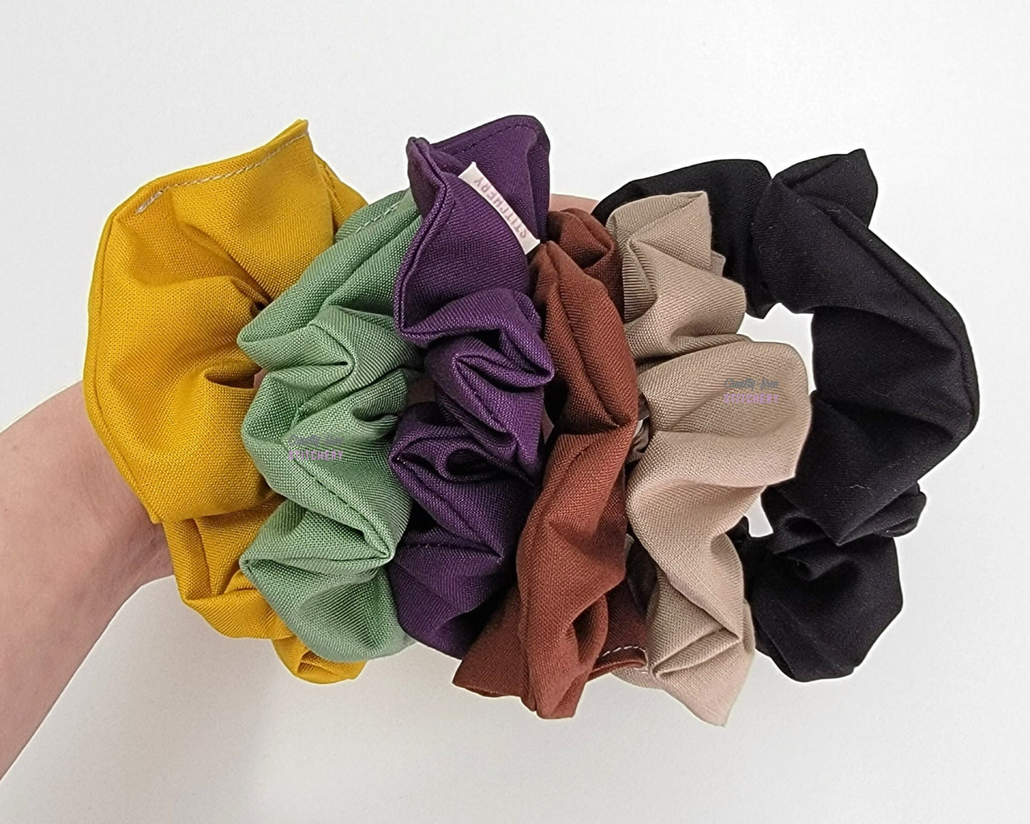 Bundle of solid color scrunchies - mustard yellow, sage green, dark purple, chocolate brown, light tan, and black.