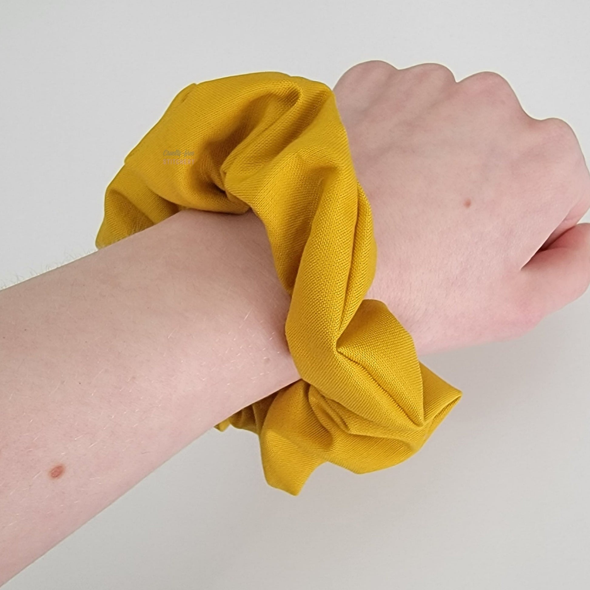 Solid mustard yellow scrunchie on my arm.