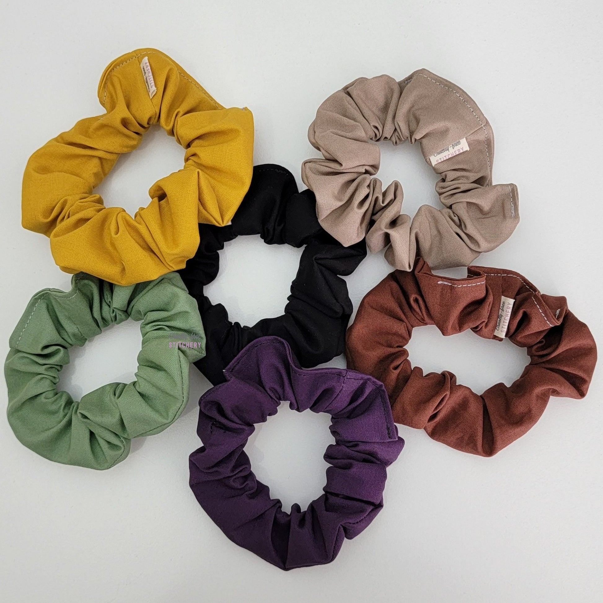 Six solid color scrunchies laid on a white background.