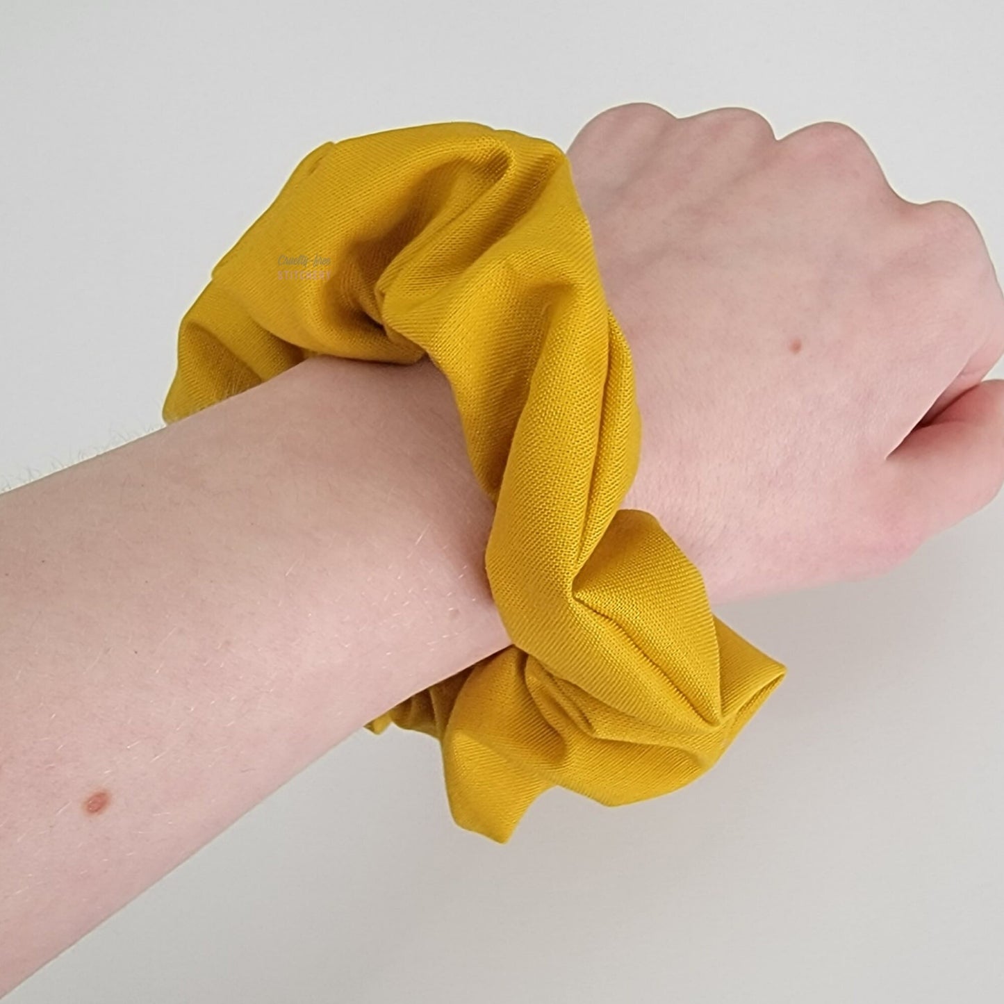 A mustard yellow scrunchie on my arm.