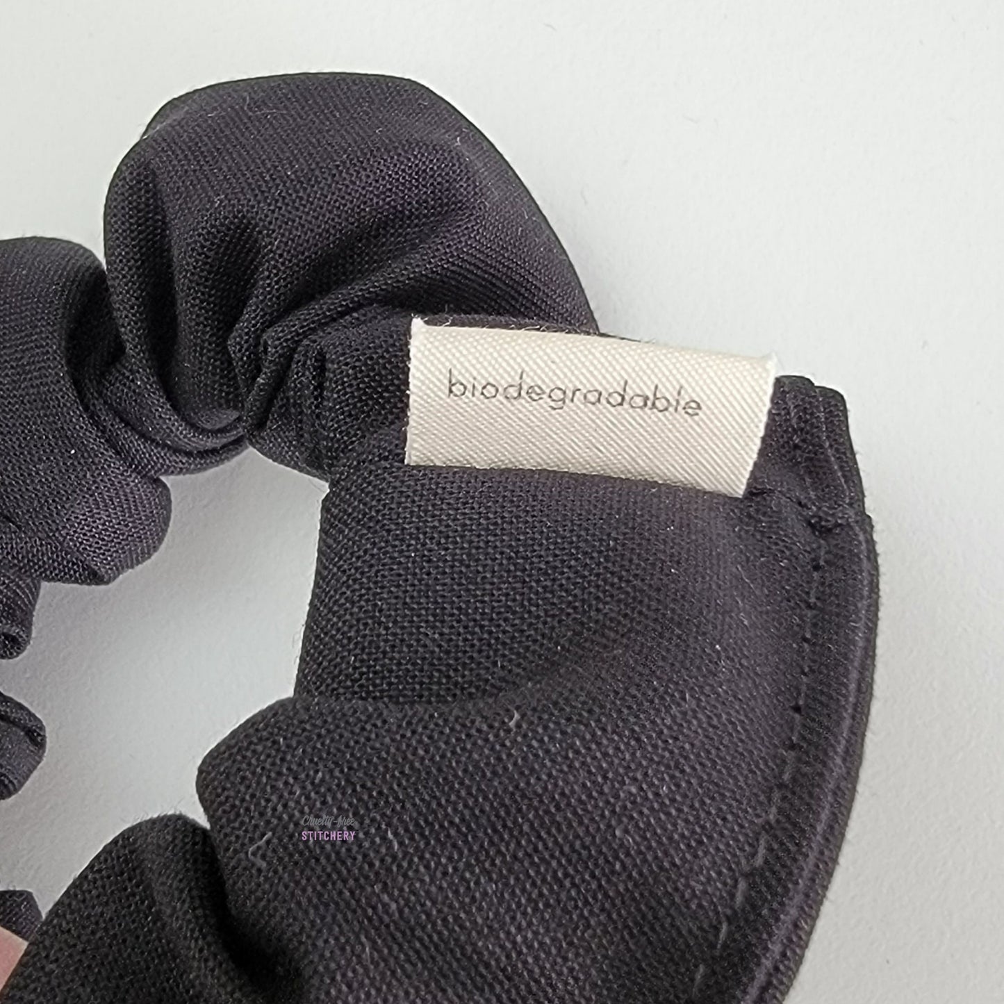 Close-up of the scrunchie, the back of the small white tag says "biodegradable".